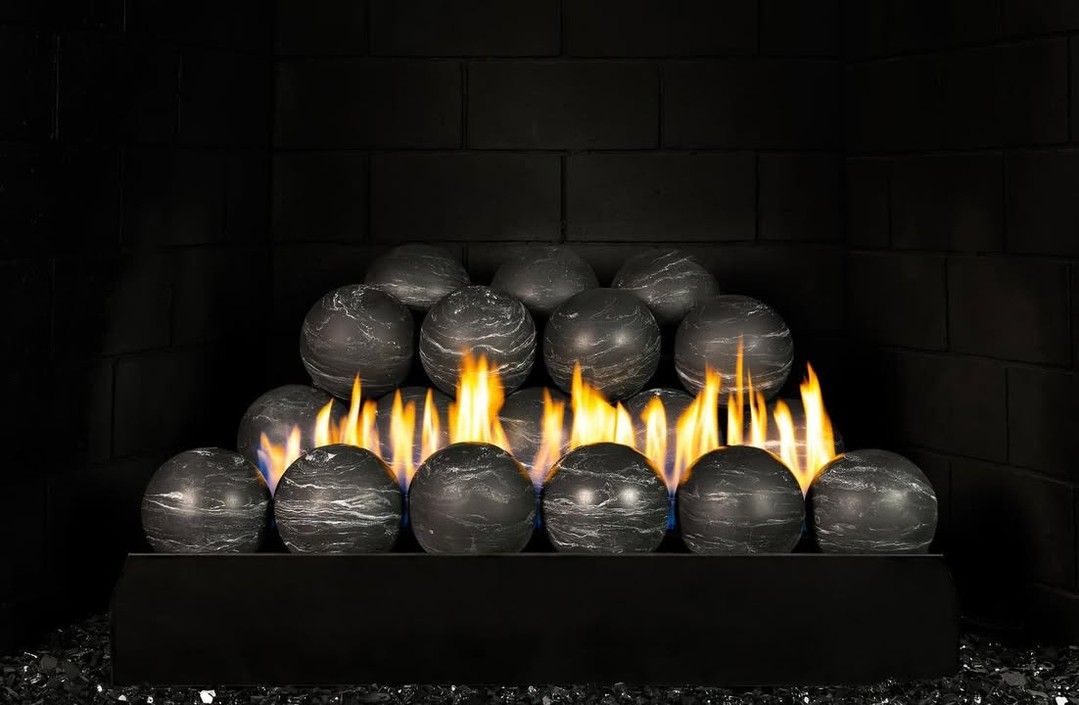 Black fire pit with glowing flames under stacked charcoal briquettes in a dark grill chamber