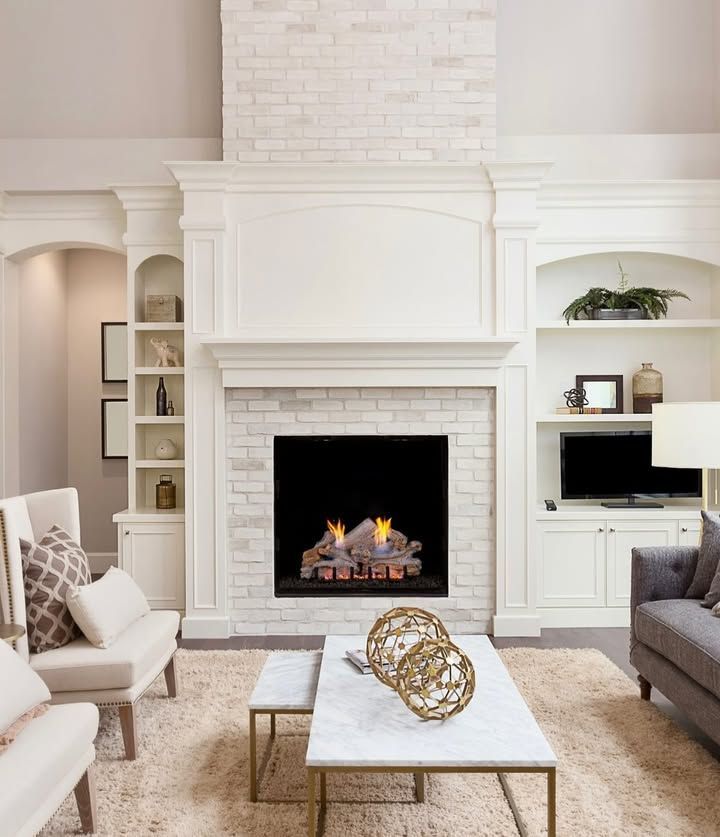 Elegant living room with white fireplace, built-in shelves, and neutral furniture around a coffee table.