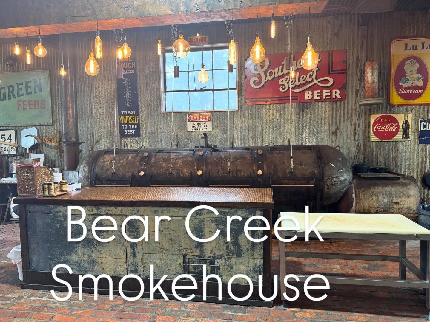 Bear Creek Smokehouse counter and sign inside a rustic restaurant interior with hanging lights and beer décor