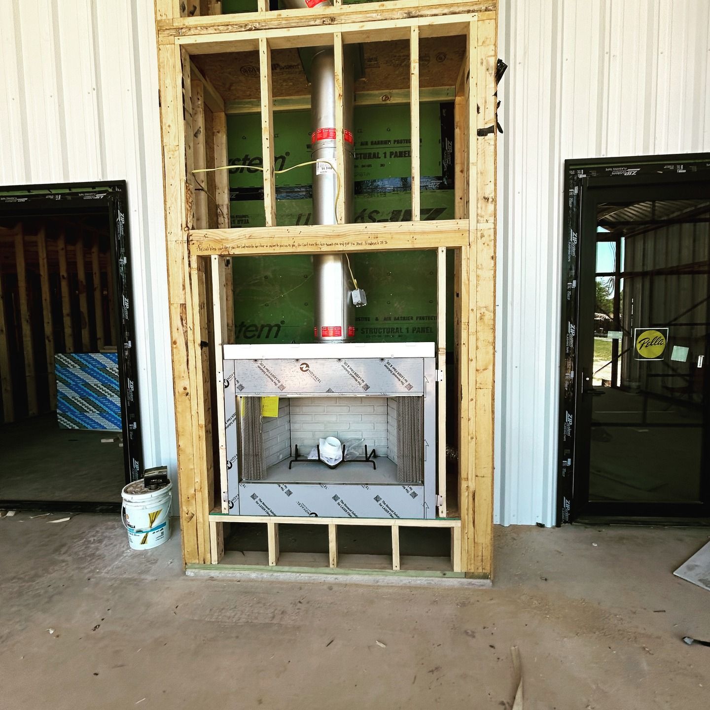 Unfinished wall with exposed framing and a metal vent duct in a construction area