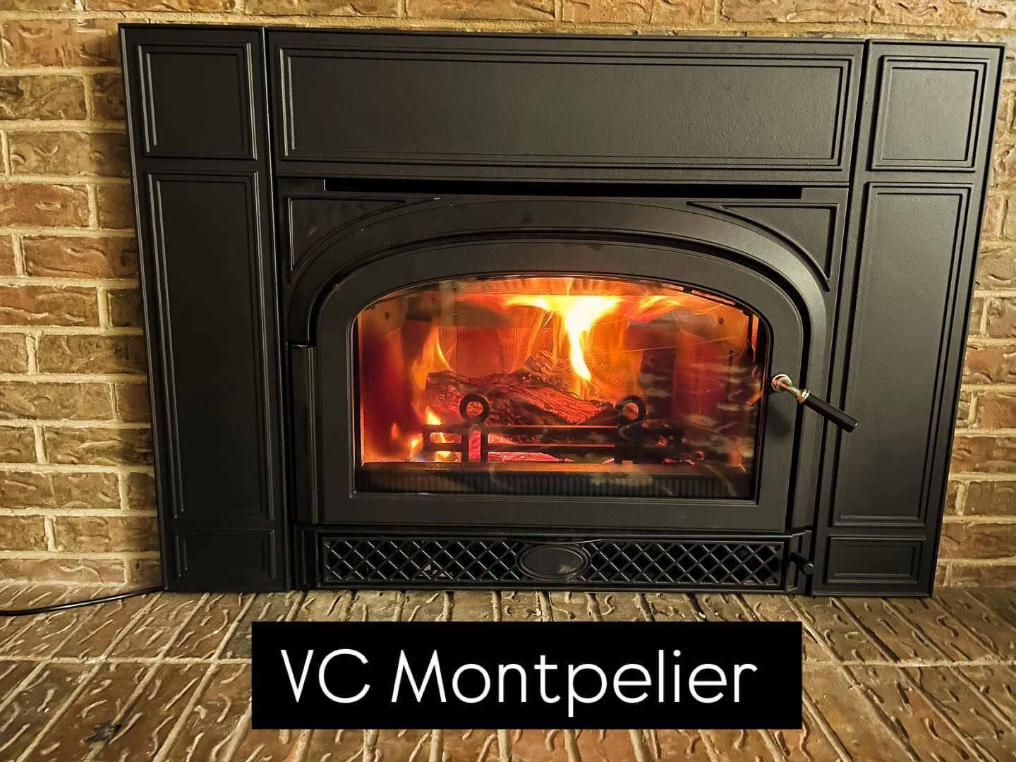 Black VC Montpelier fireplace with bright flames in a brick-walled room