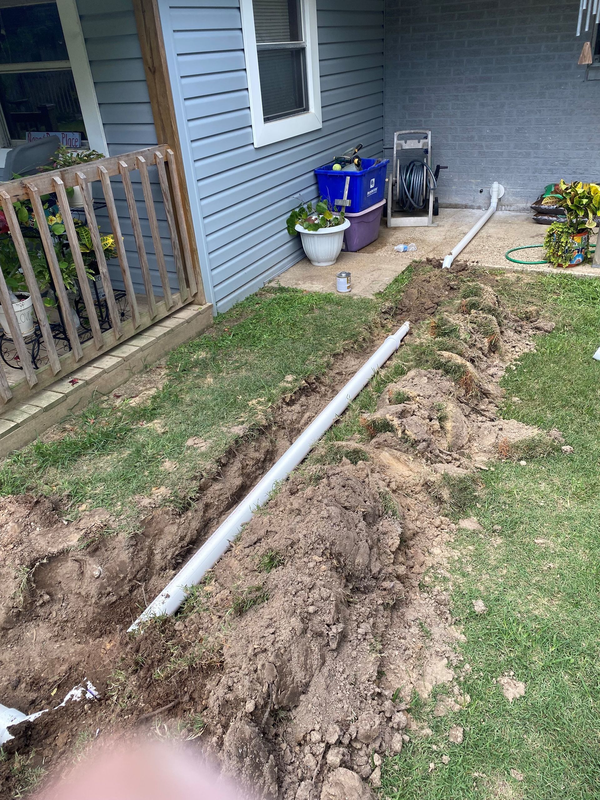 A drain pipe is being installed in the backyard of a house.