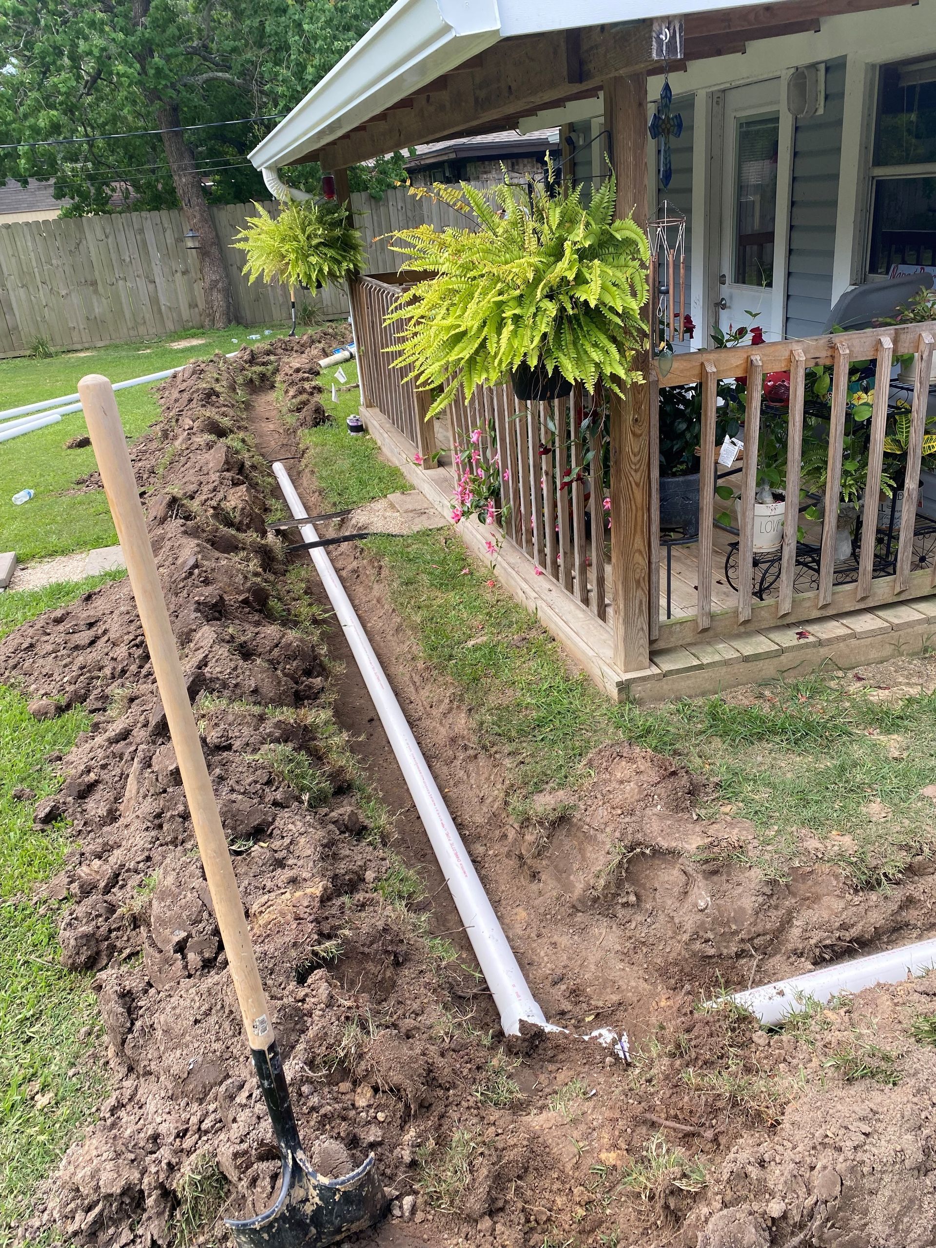 A shovel is sitting in the dirt in front of a house.
