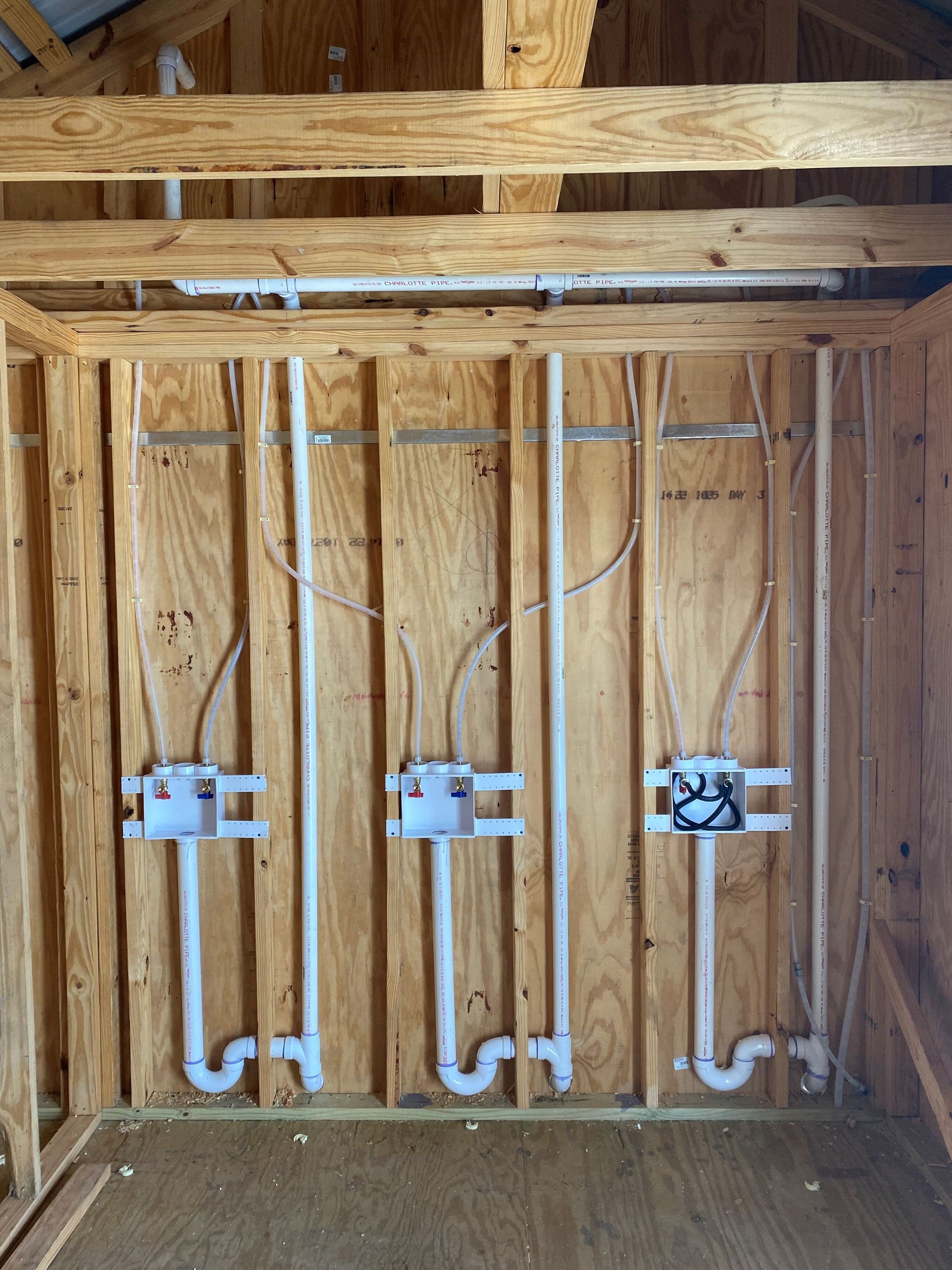 A wooden wall with a lot of pipes coming out of it.