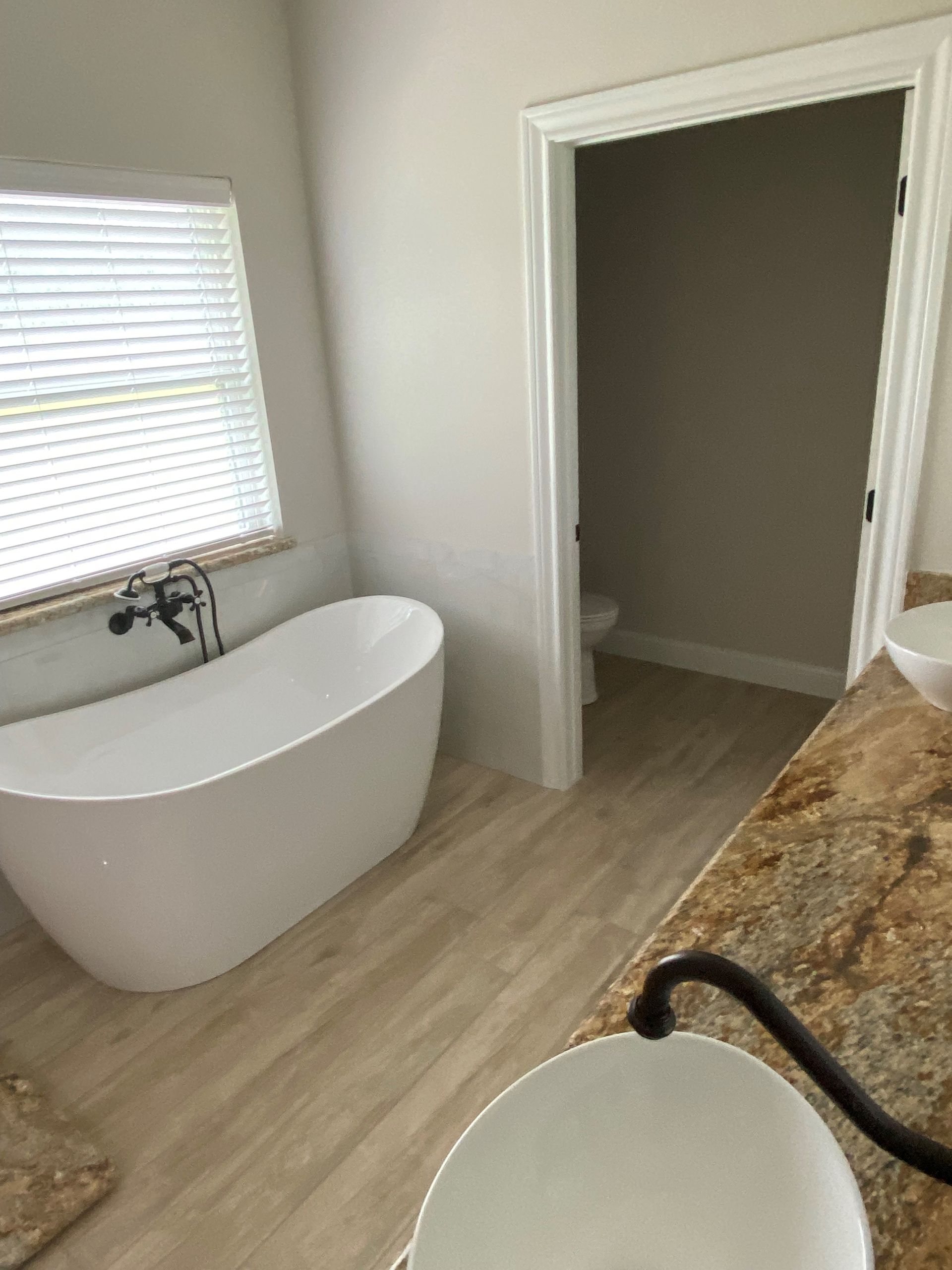 A bathroom with a tub , sink , toilet and window.