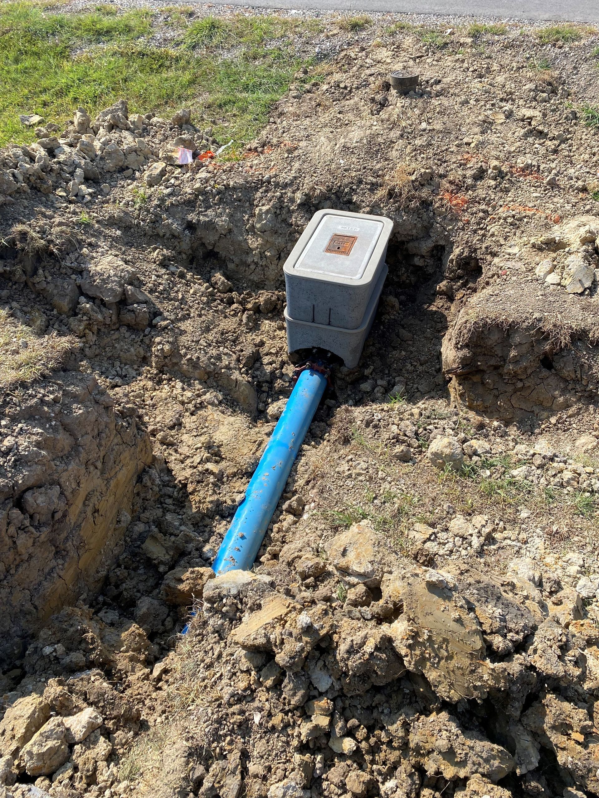 A blue pipe is sitting in the middle of a pile of dirt.