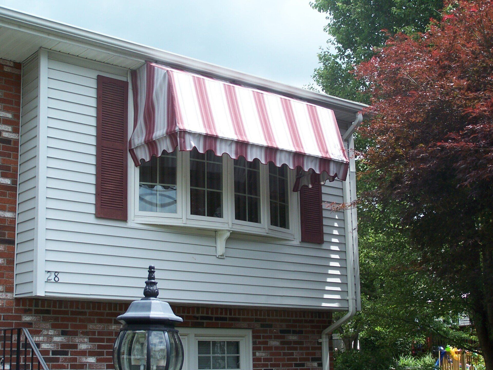 A white house with a red and white awning over a window