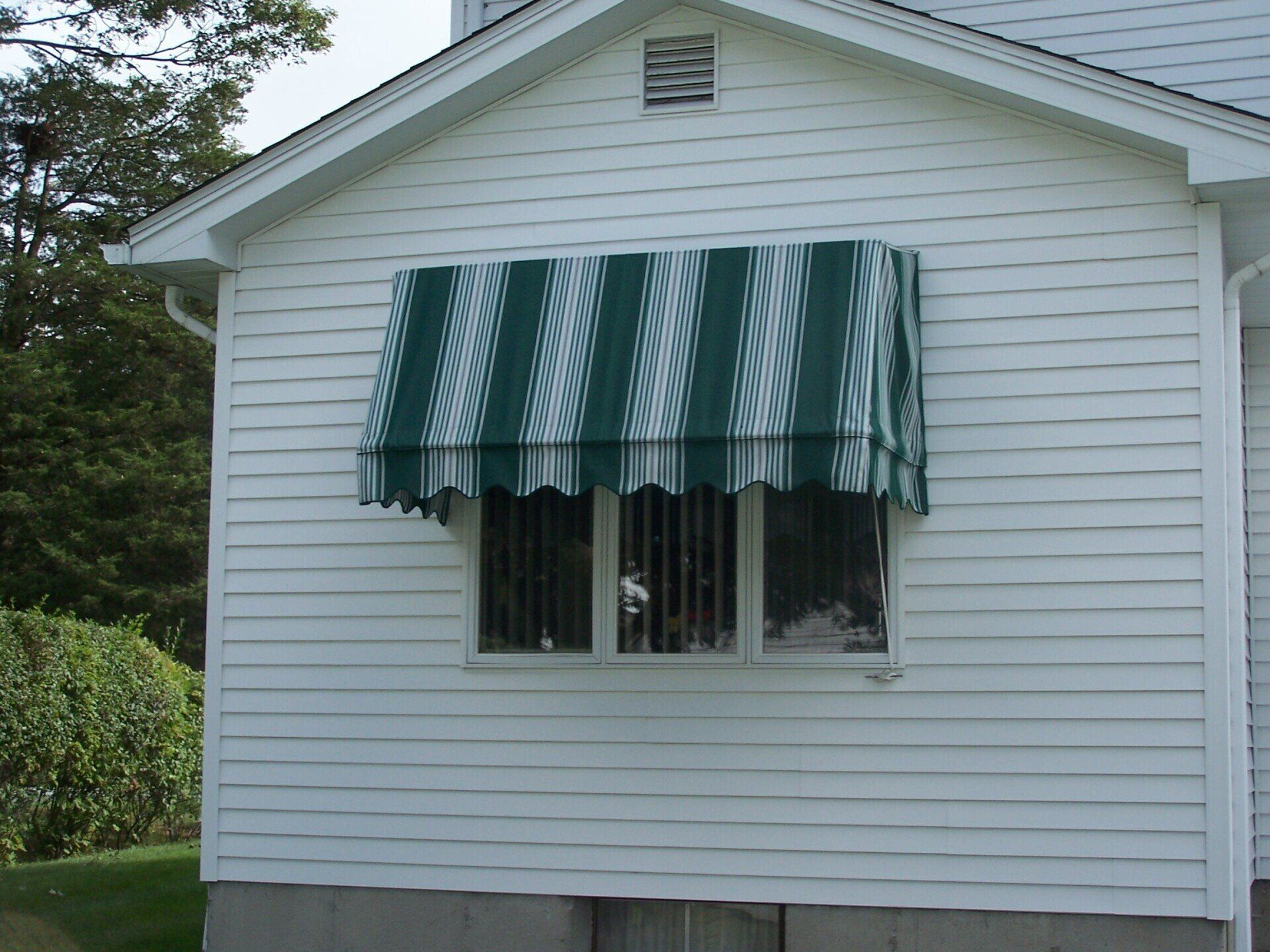 A white house with a green and white awning over a window
