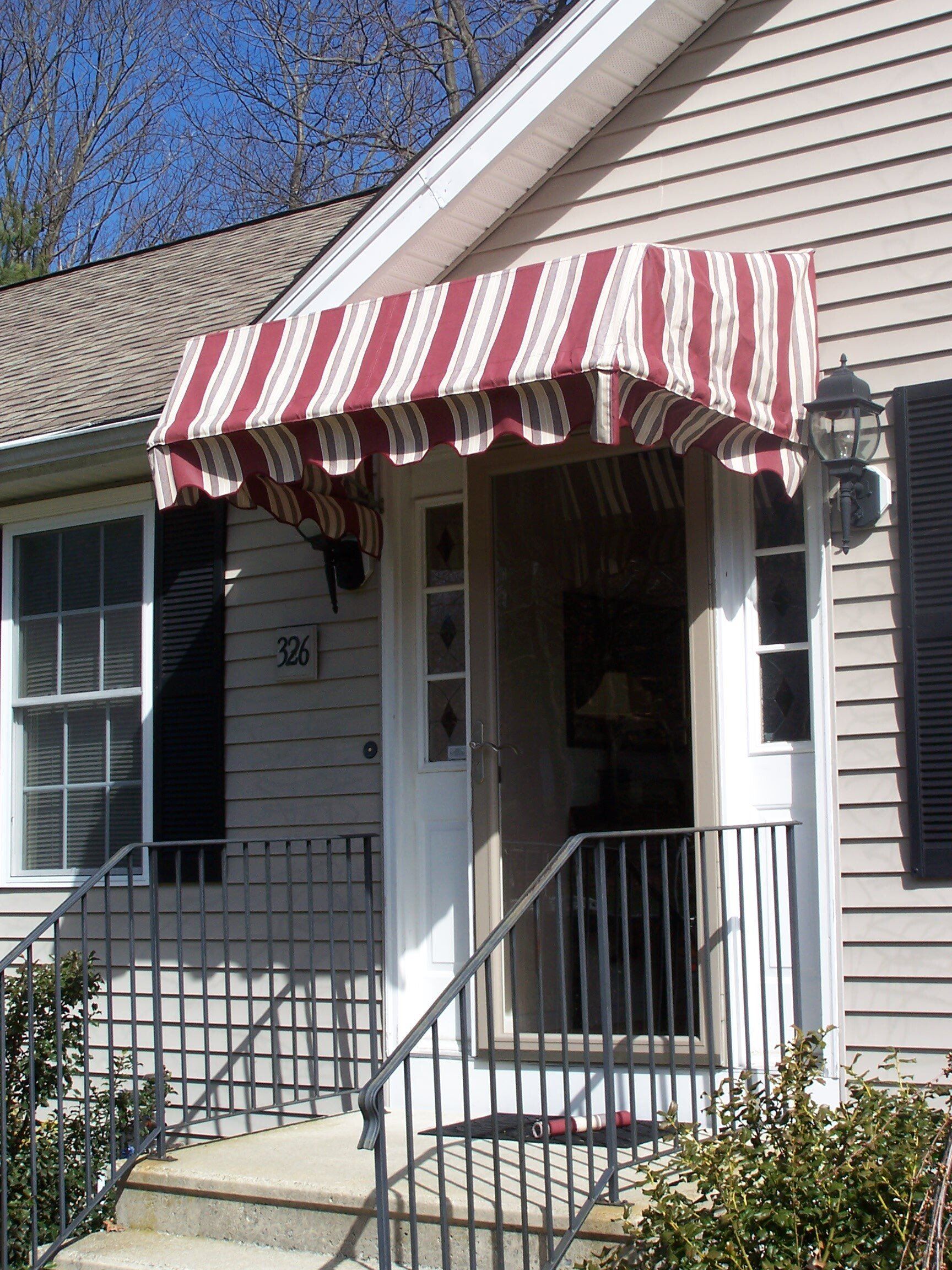 A house with a red and white awning over the front door