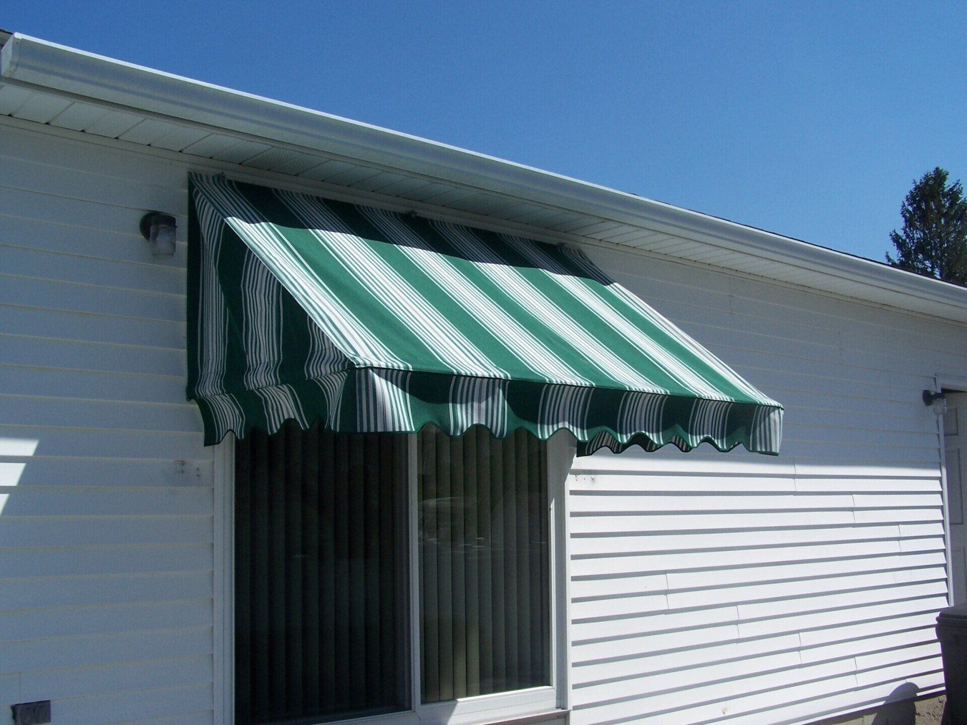 A white house with a green and white awning over a window