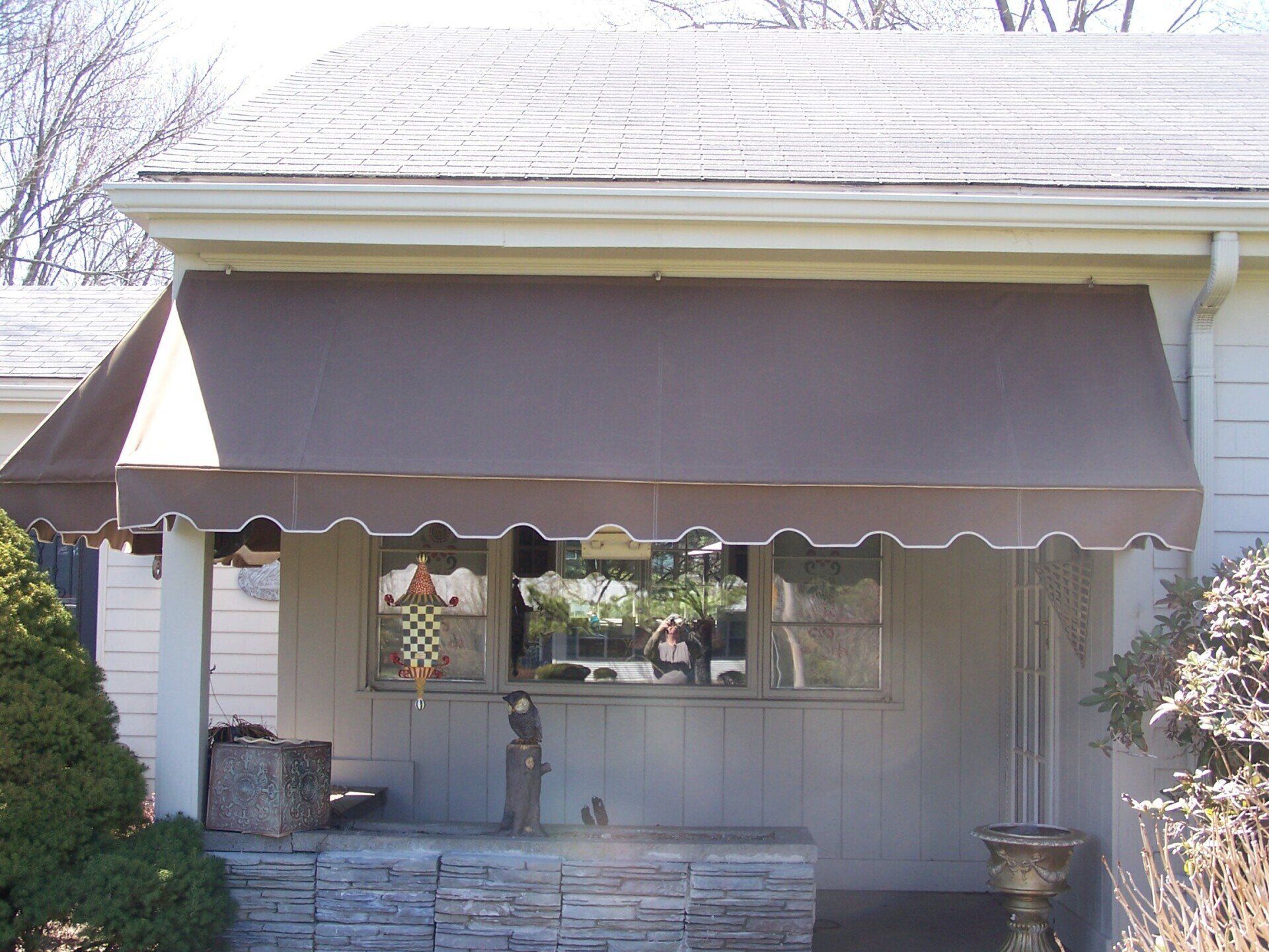 A white house with a brown awning on the porch.