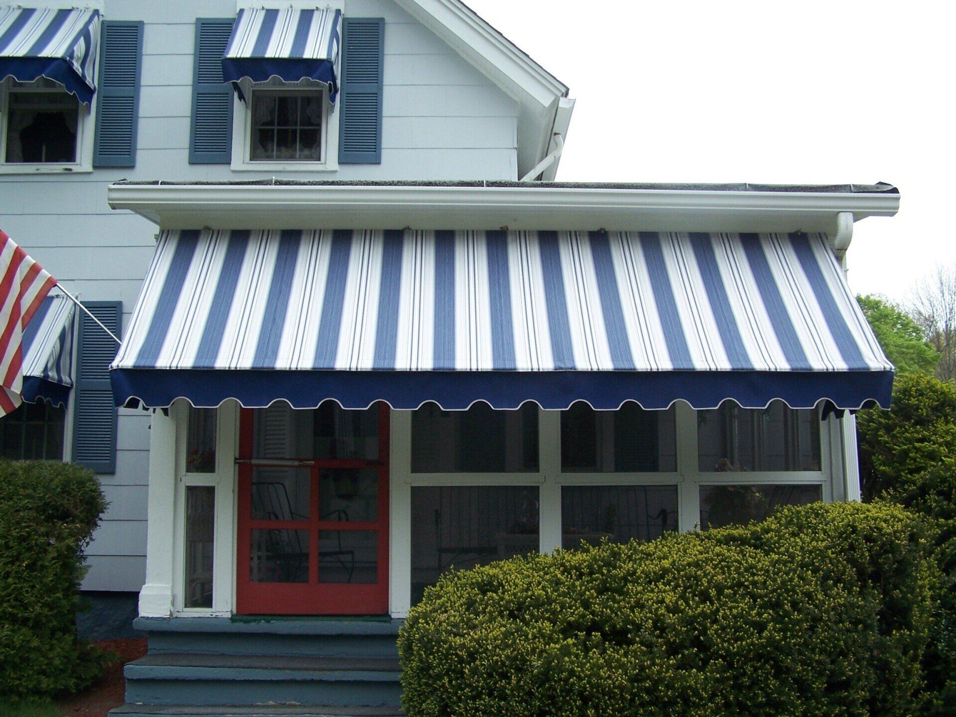 A house with a blue and white striped awning over the porch
