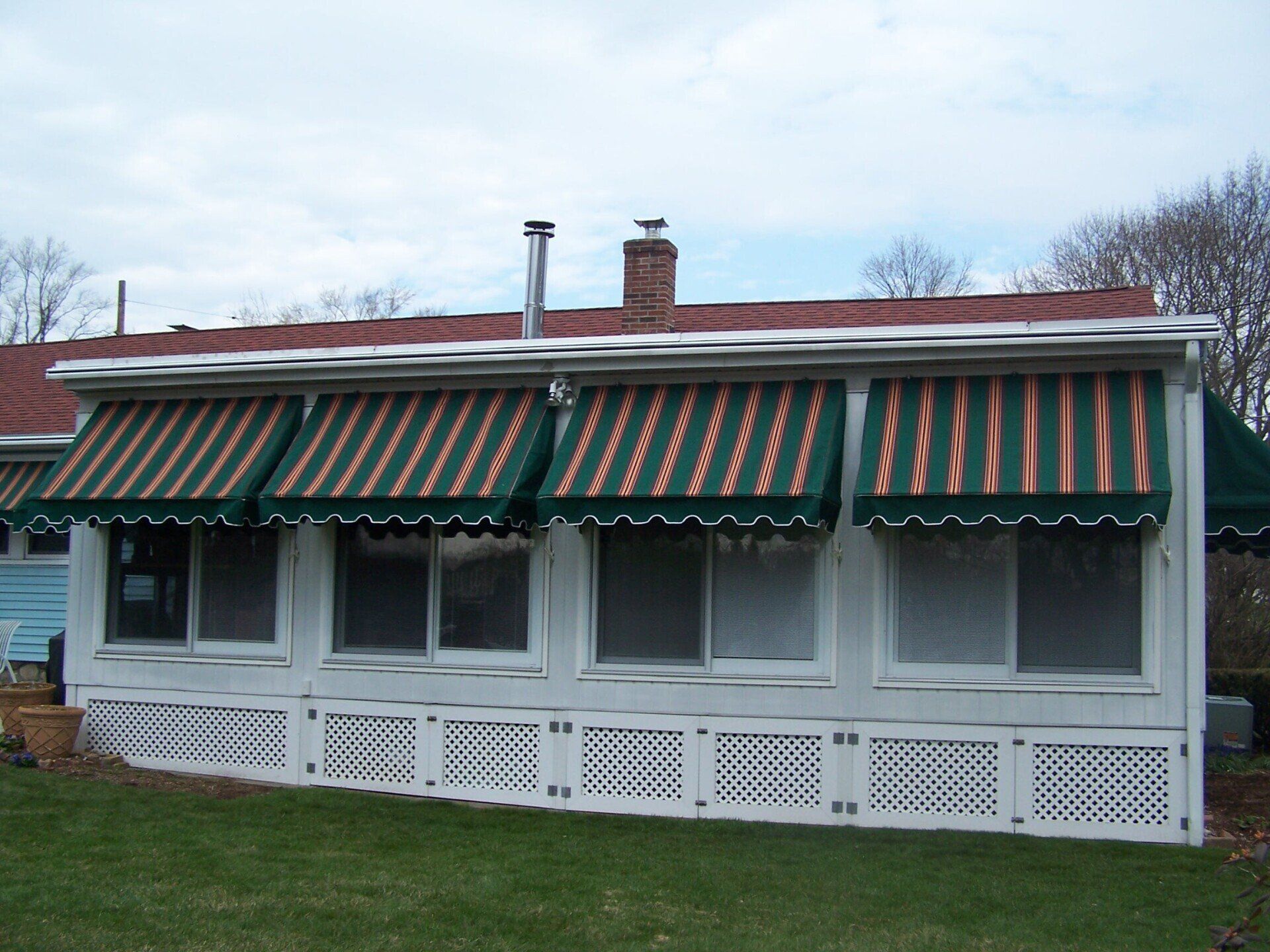 A white house with green and yellow awnings on the windows