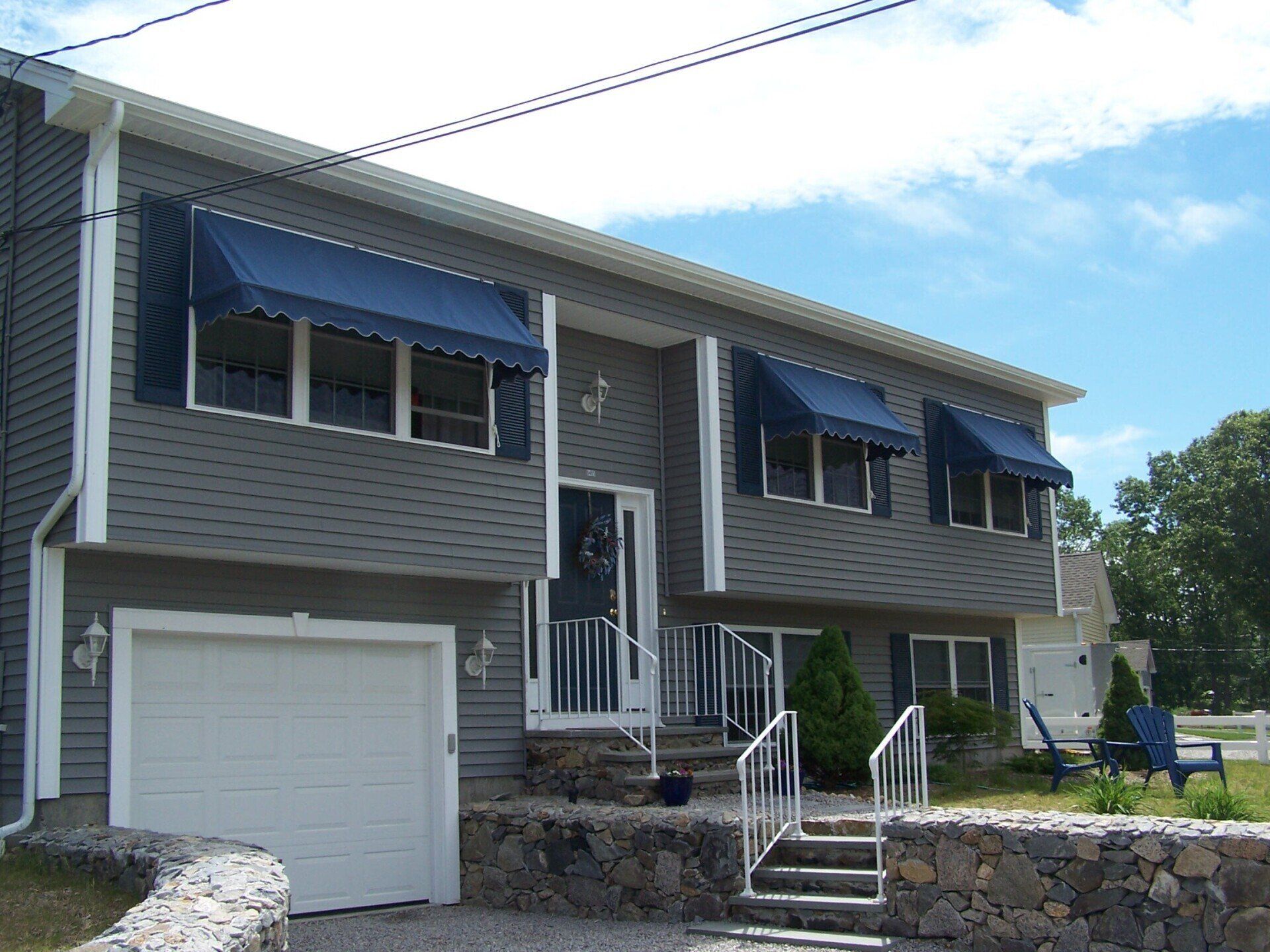 A house with a white garage door and blue awnings