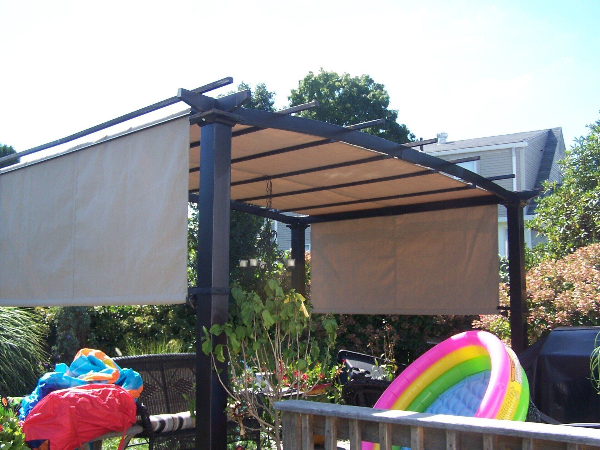 An inflatable pool sits under a canopy on a deck
