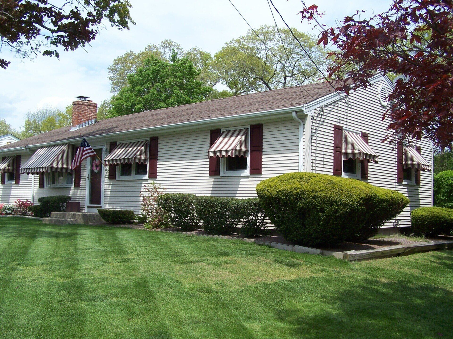 A white house with red and white awnings on the windows