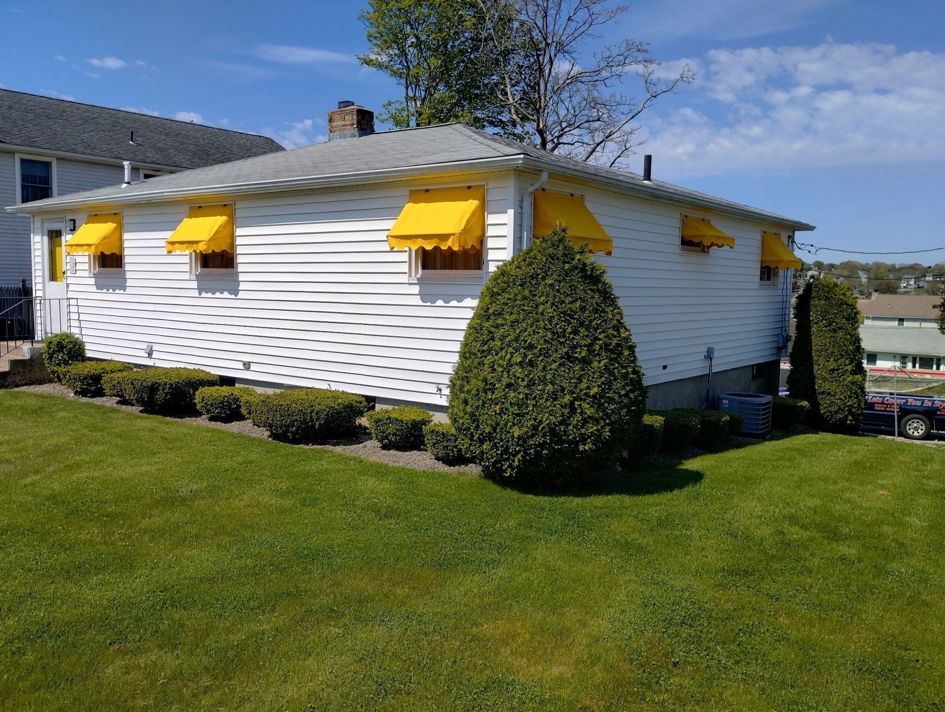 A white house with yellow awnings on the windows