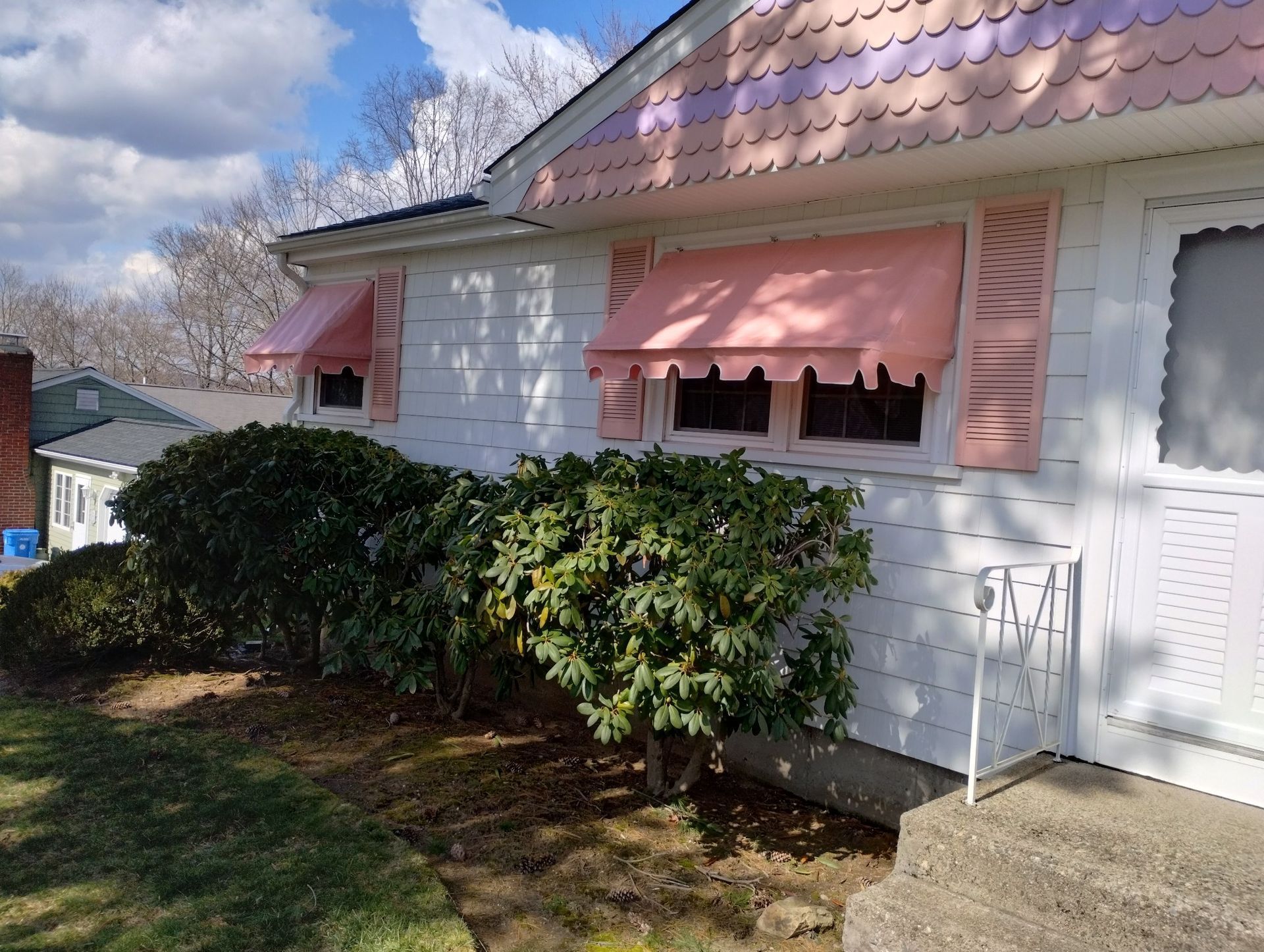 A white house with pink awnings on the windows