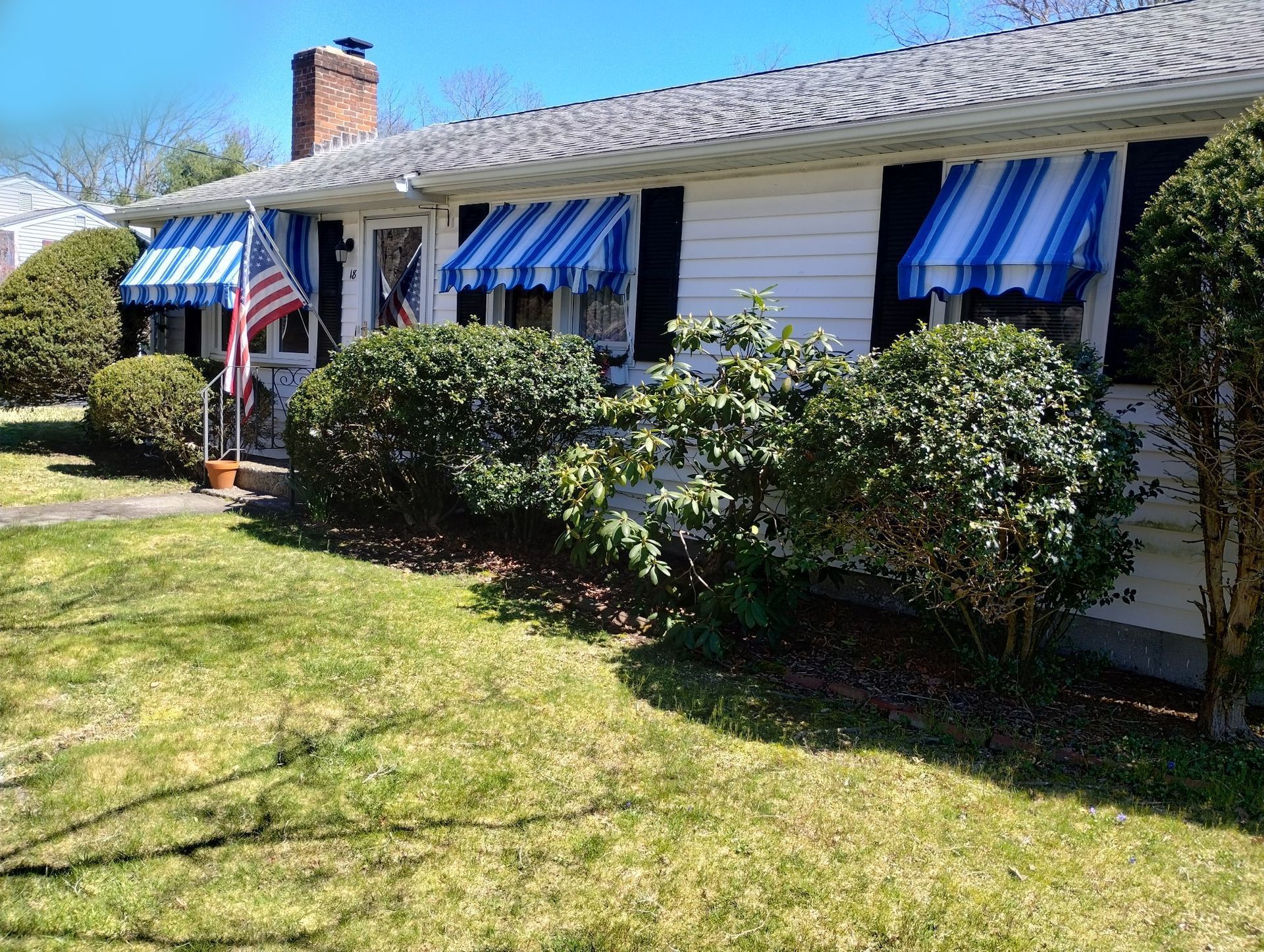 A white house with blue and white awnings on the windows