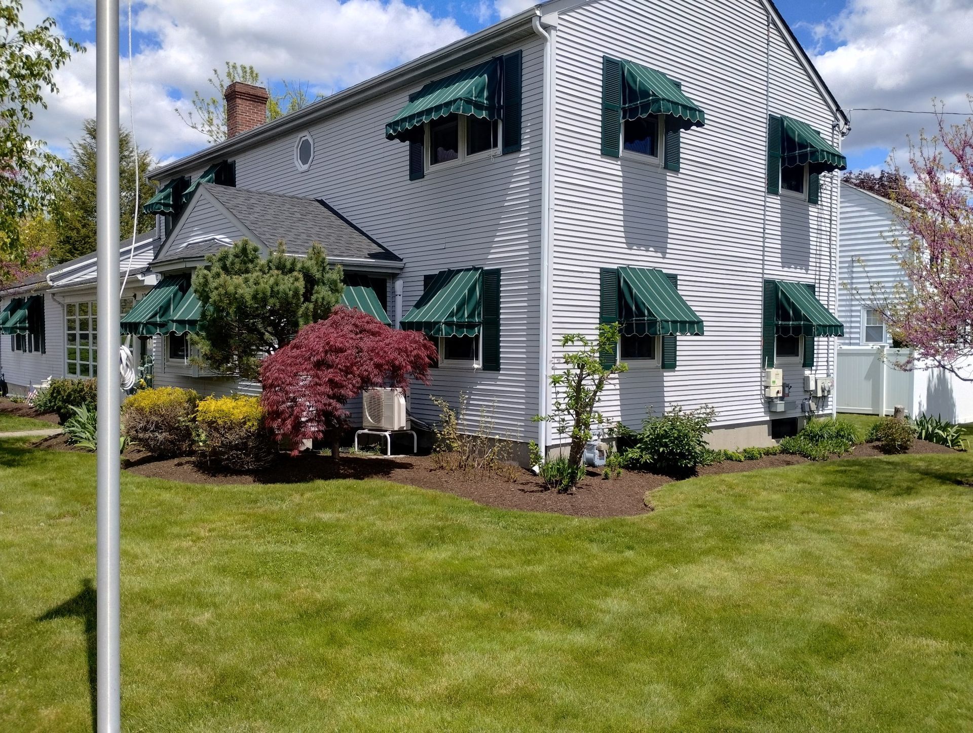 A white house with green awnings on the windows