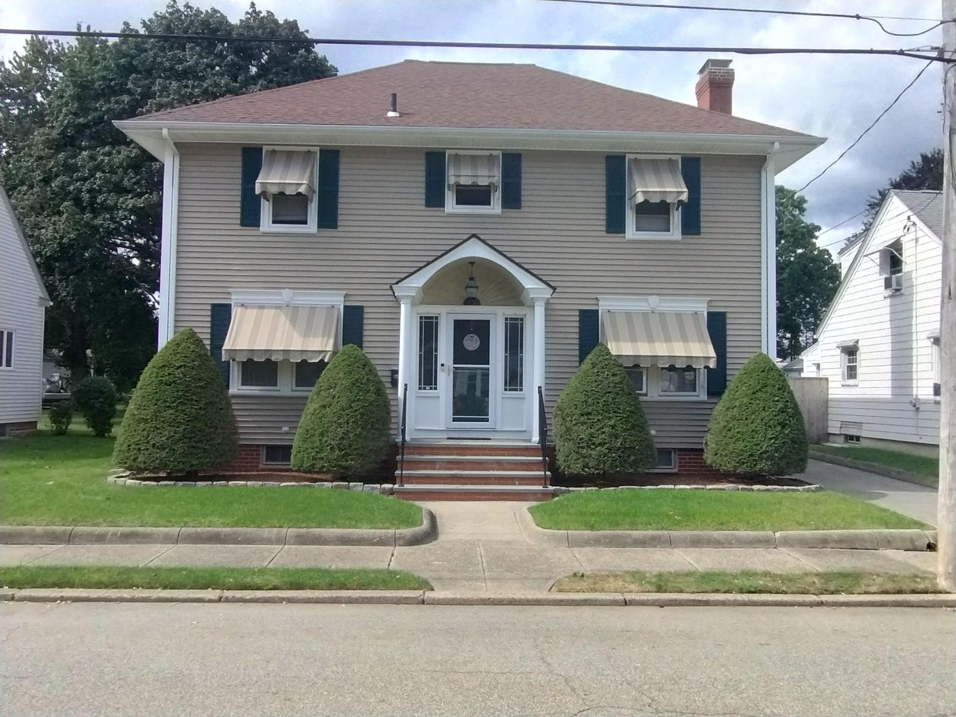 A house with a porch and awnings on the windows