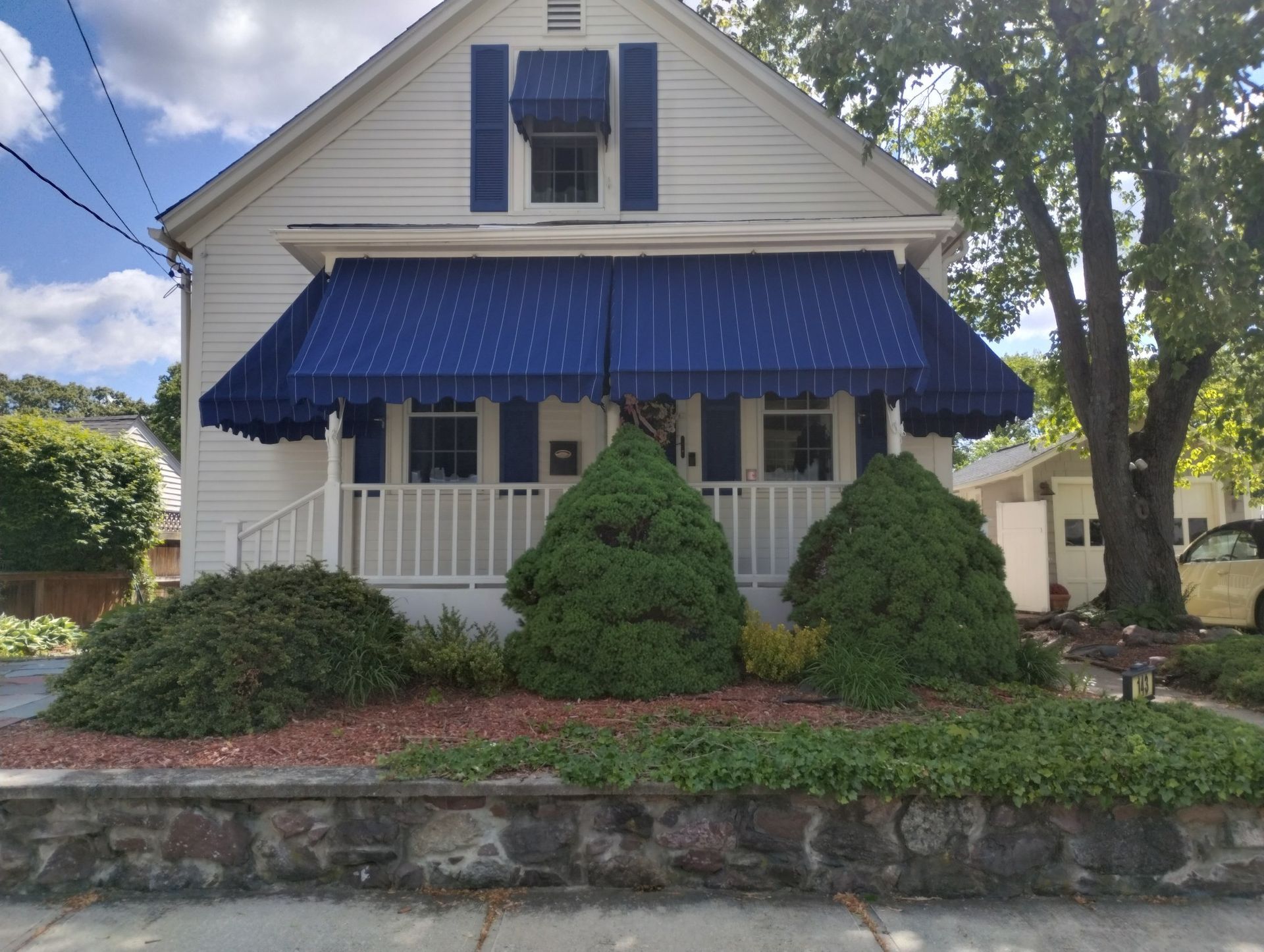 A white house with a blue awning on the porch