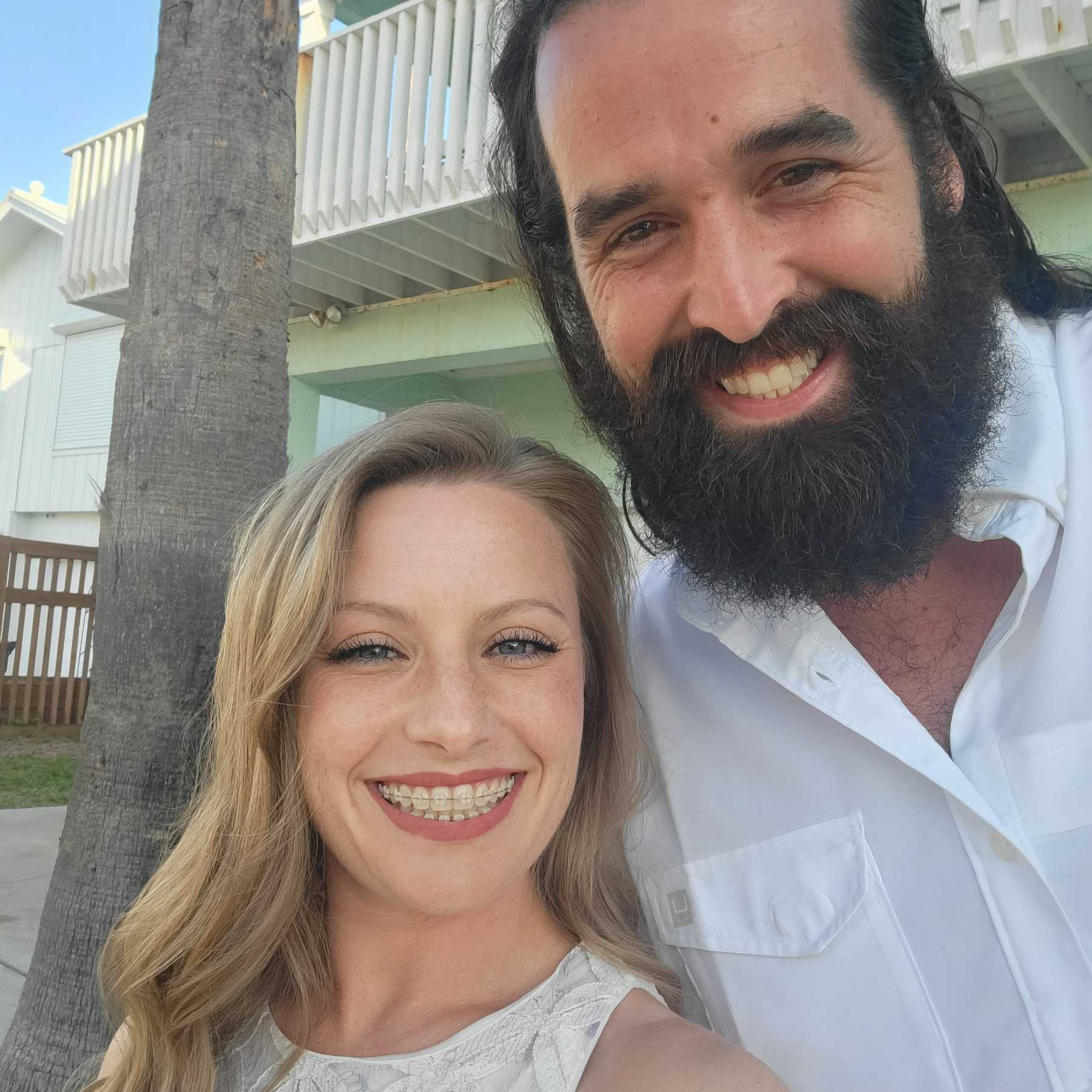 A man with a beard and a woman with braces smile for the camera