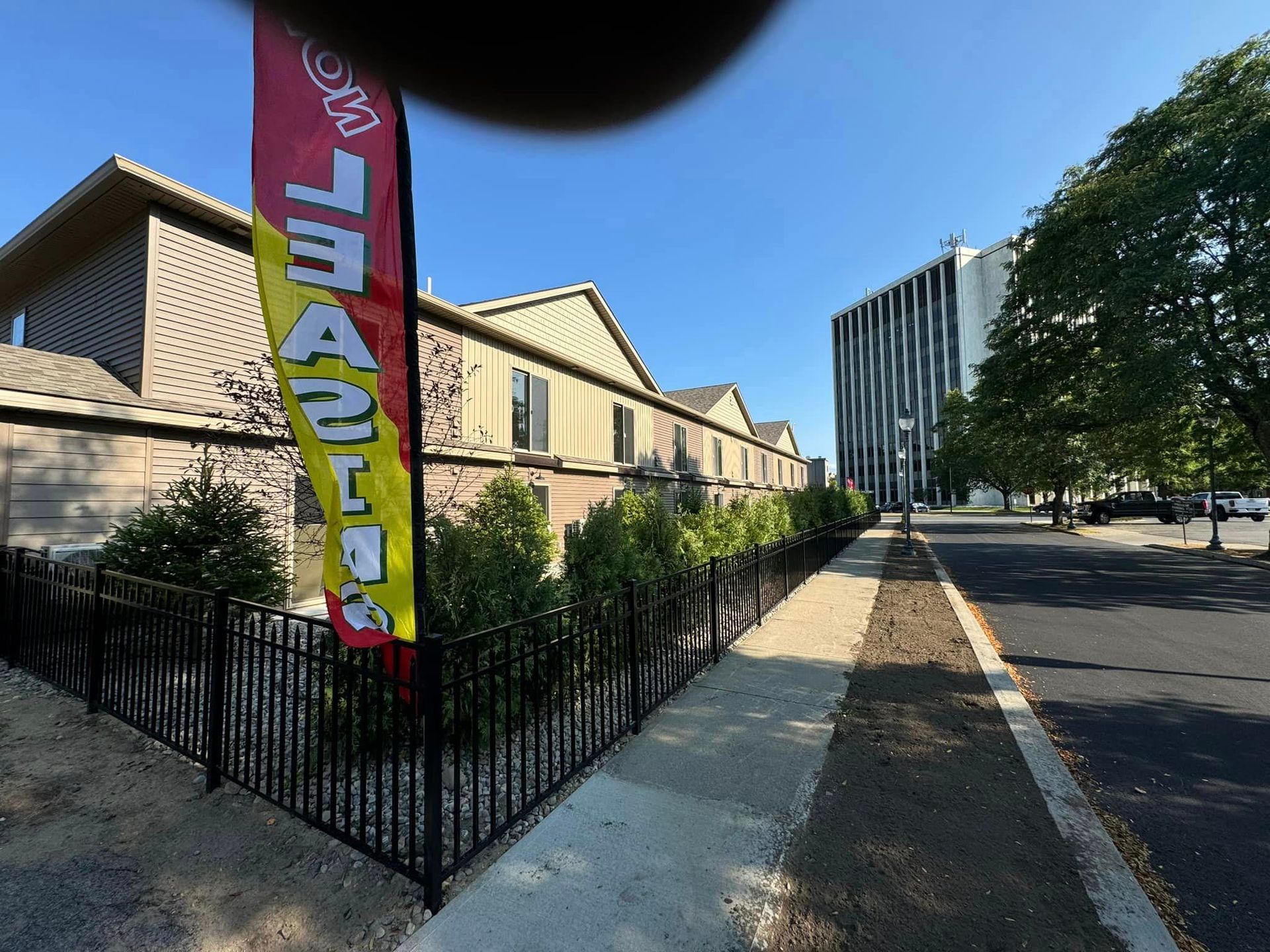 A red and yellow flag on black fence along a sidewalk