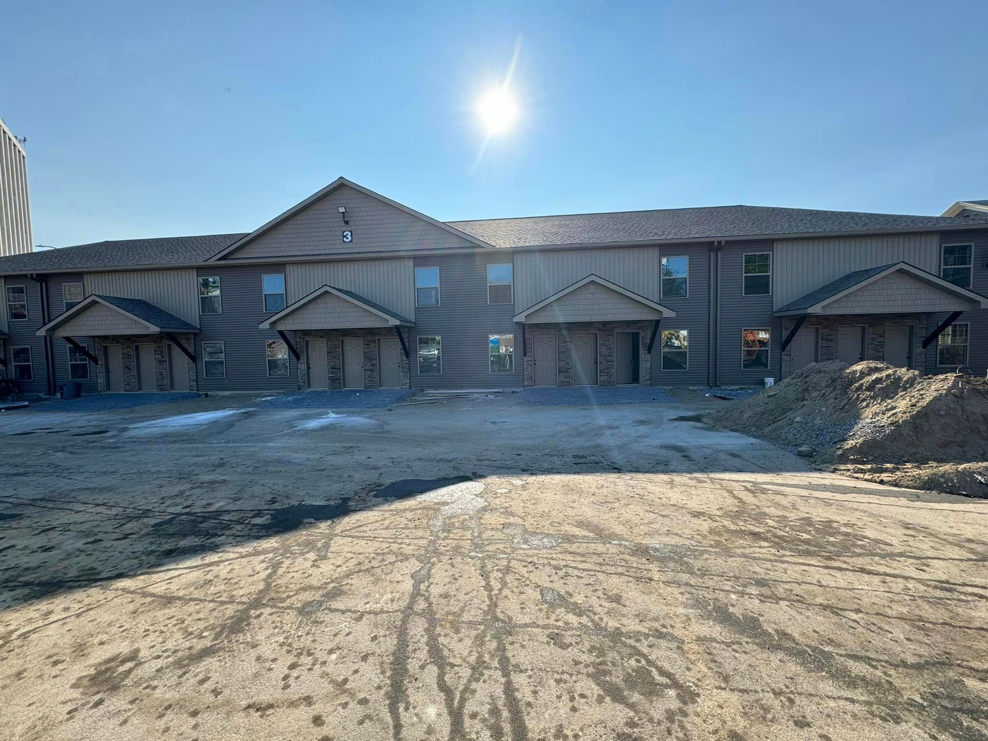 A large apartment building under construction with a lot of dirt in front of it