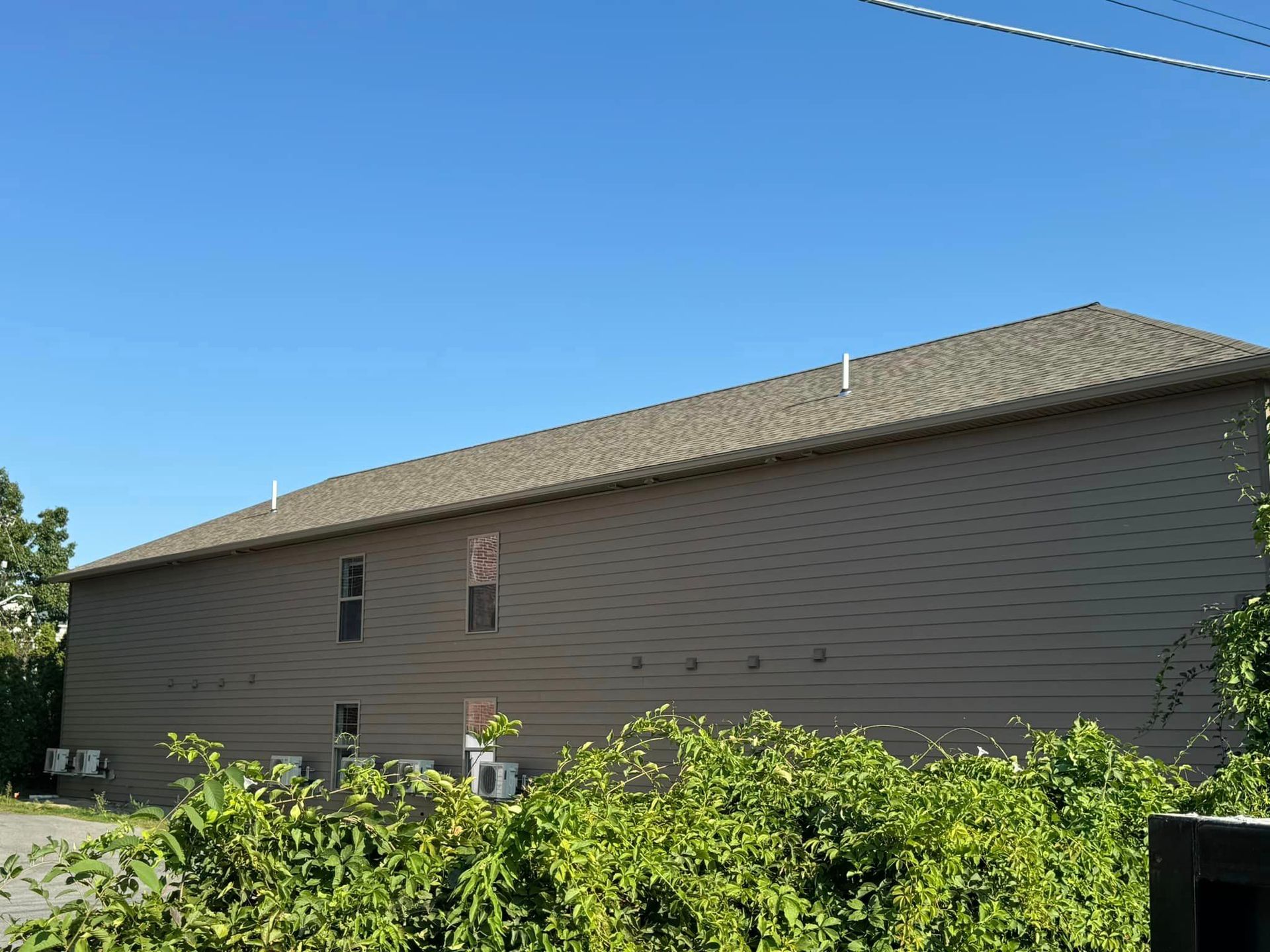 The back of a large building with a roof that is covered in shingles