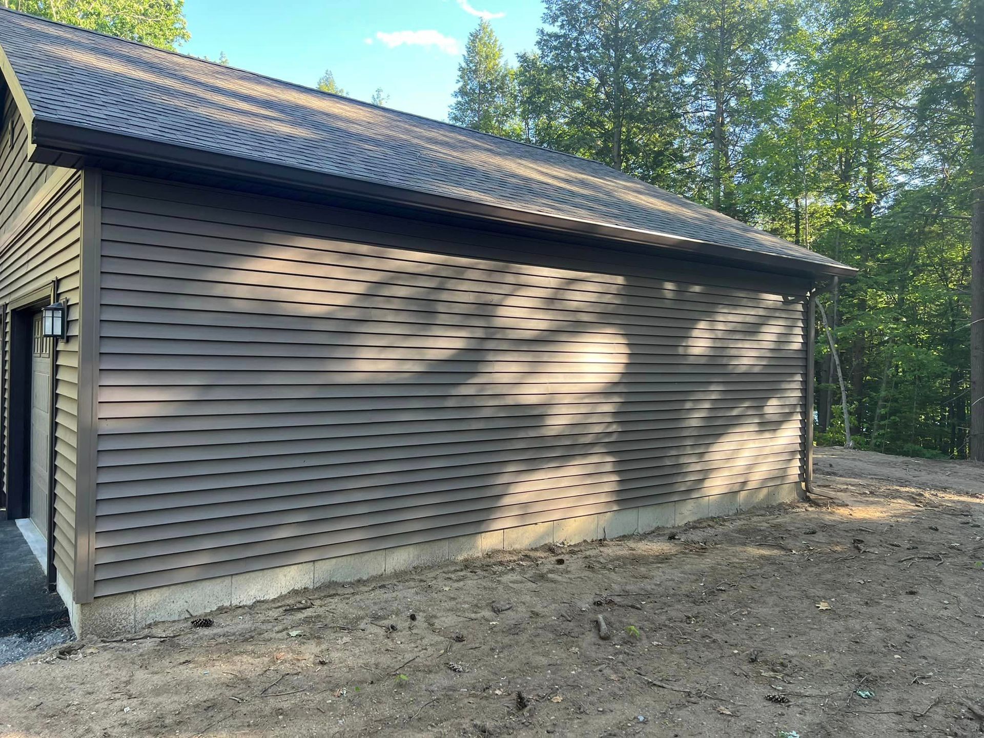 A large brown building with a roof is sitting in the middle of a dirt field