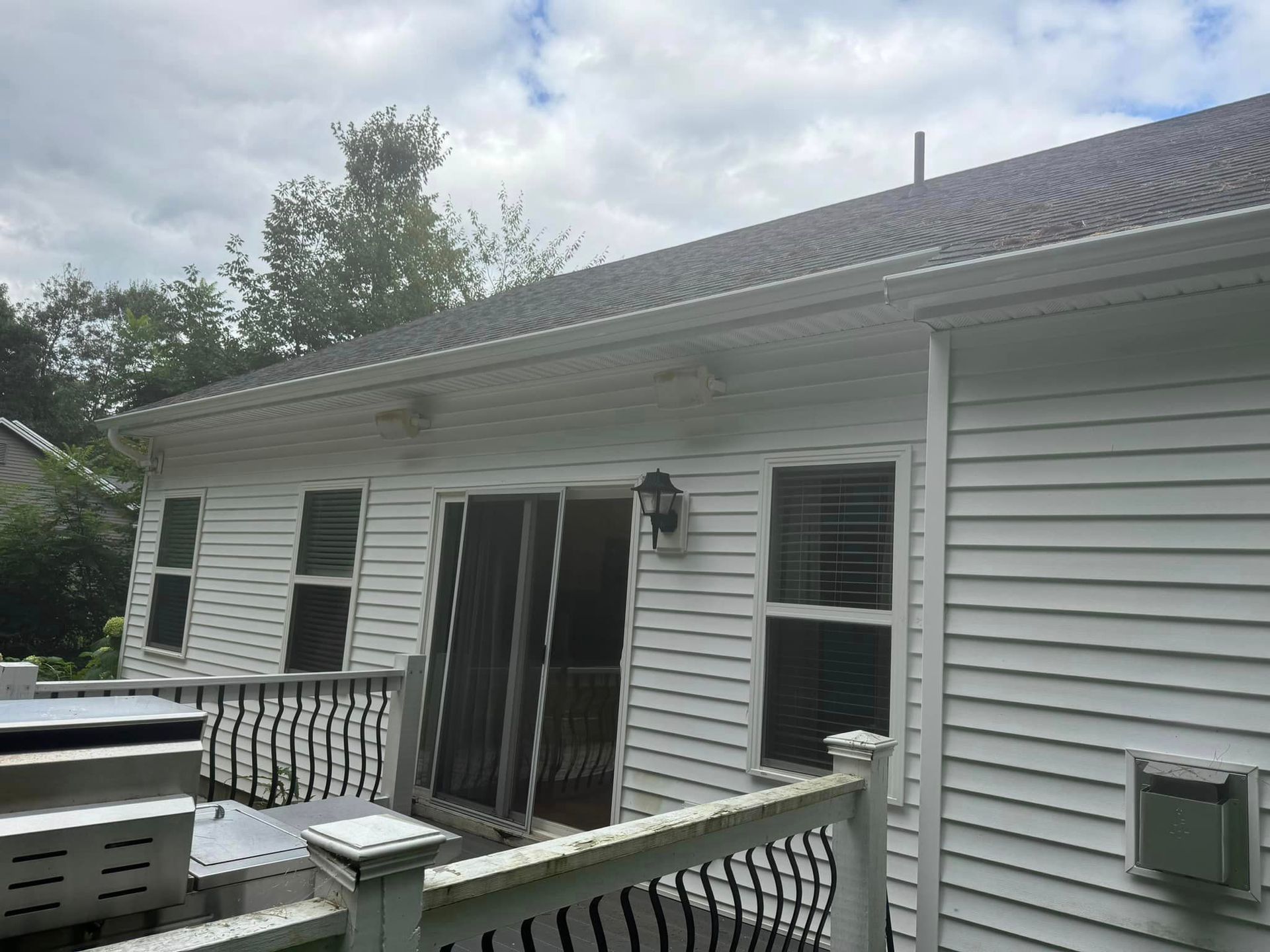 The back of a white house with a deck and a hot tub