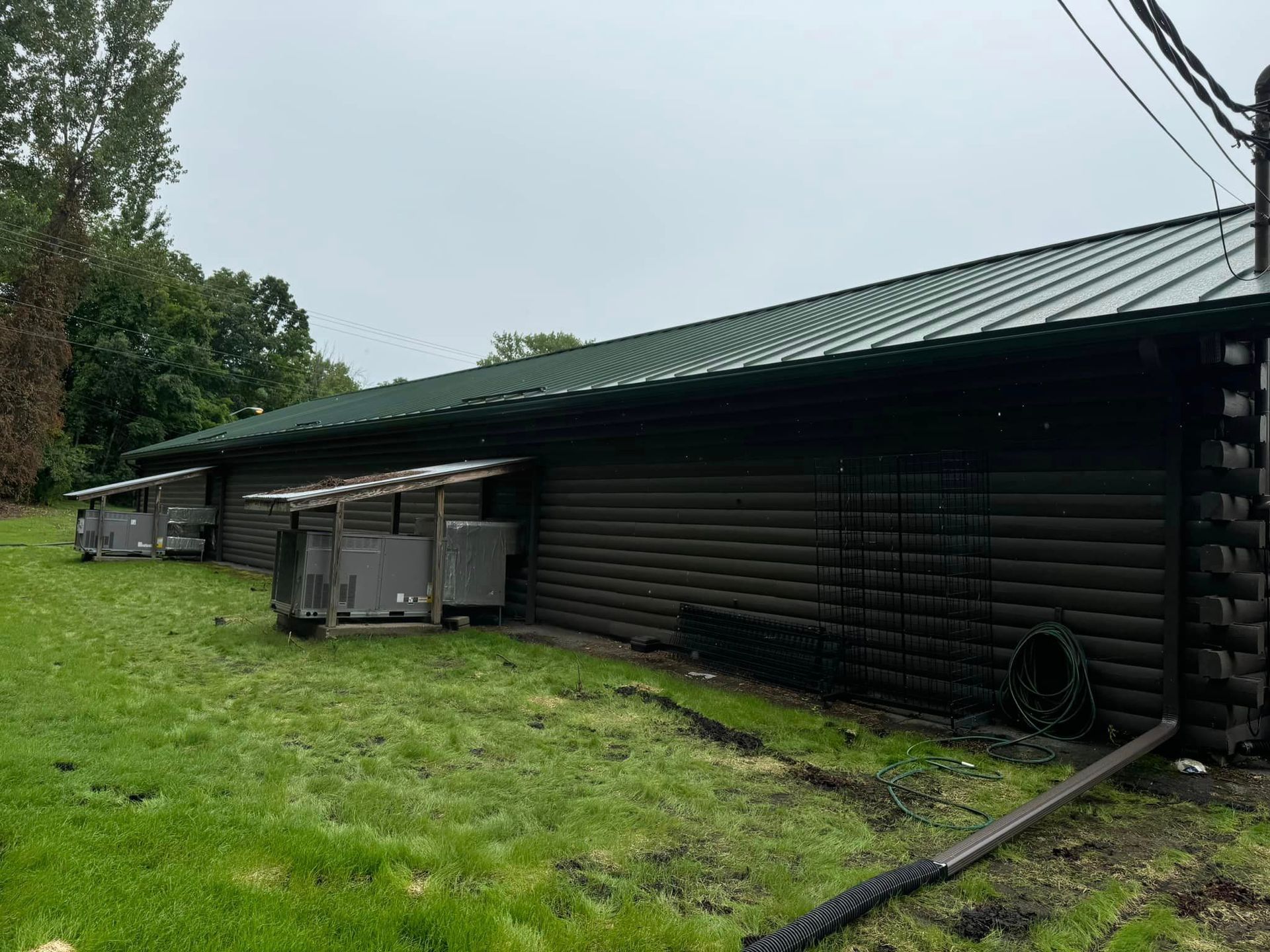 A log cabin with a green roof is sitting in the middle of a grassy field