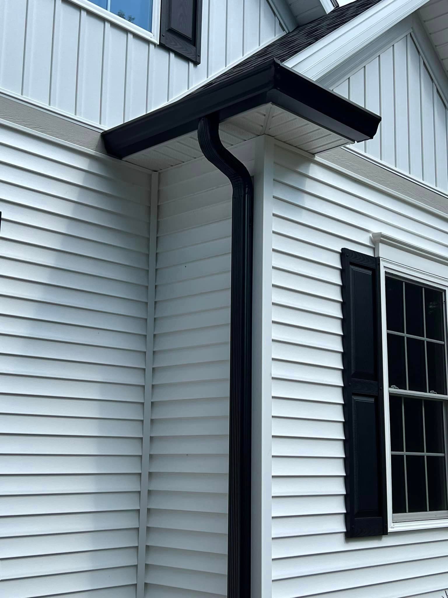 A white house with a black gutter and black shutters