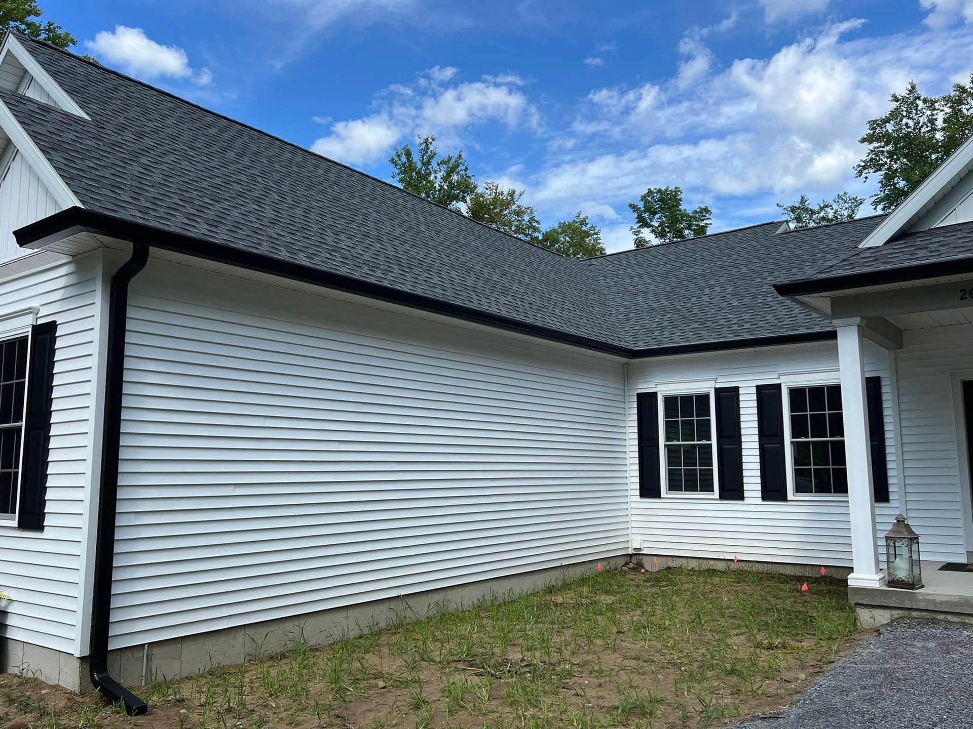 A white house with black shutters and a gray roof