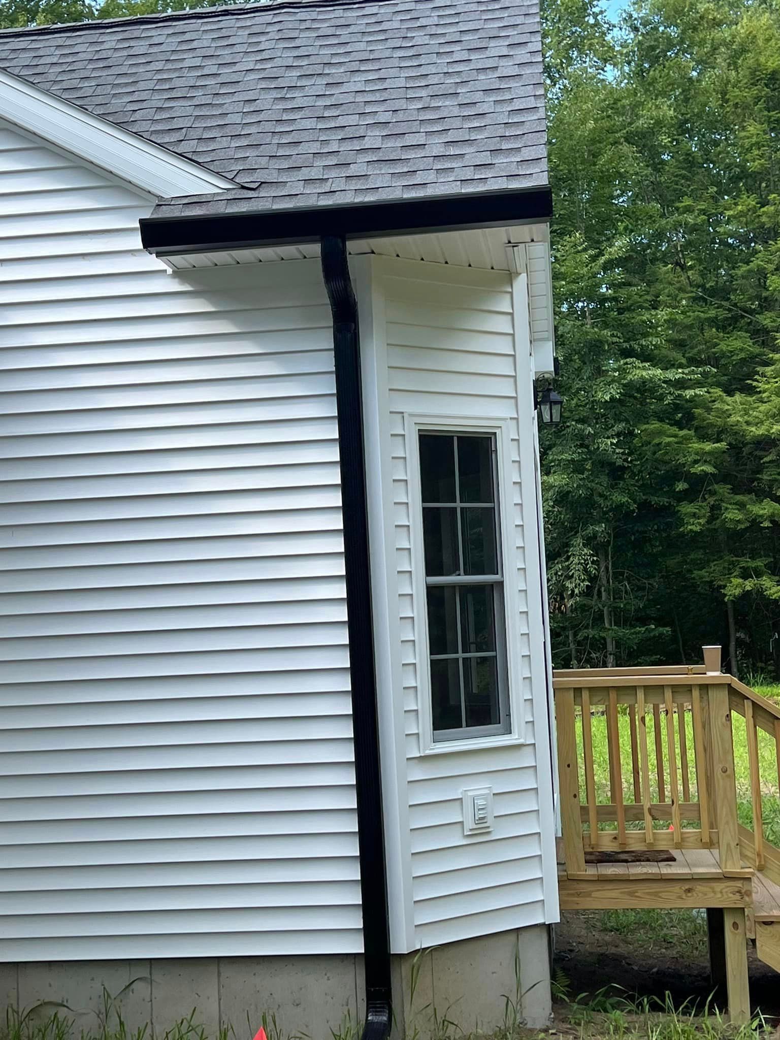 A white house with a black gutter and a window