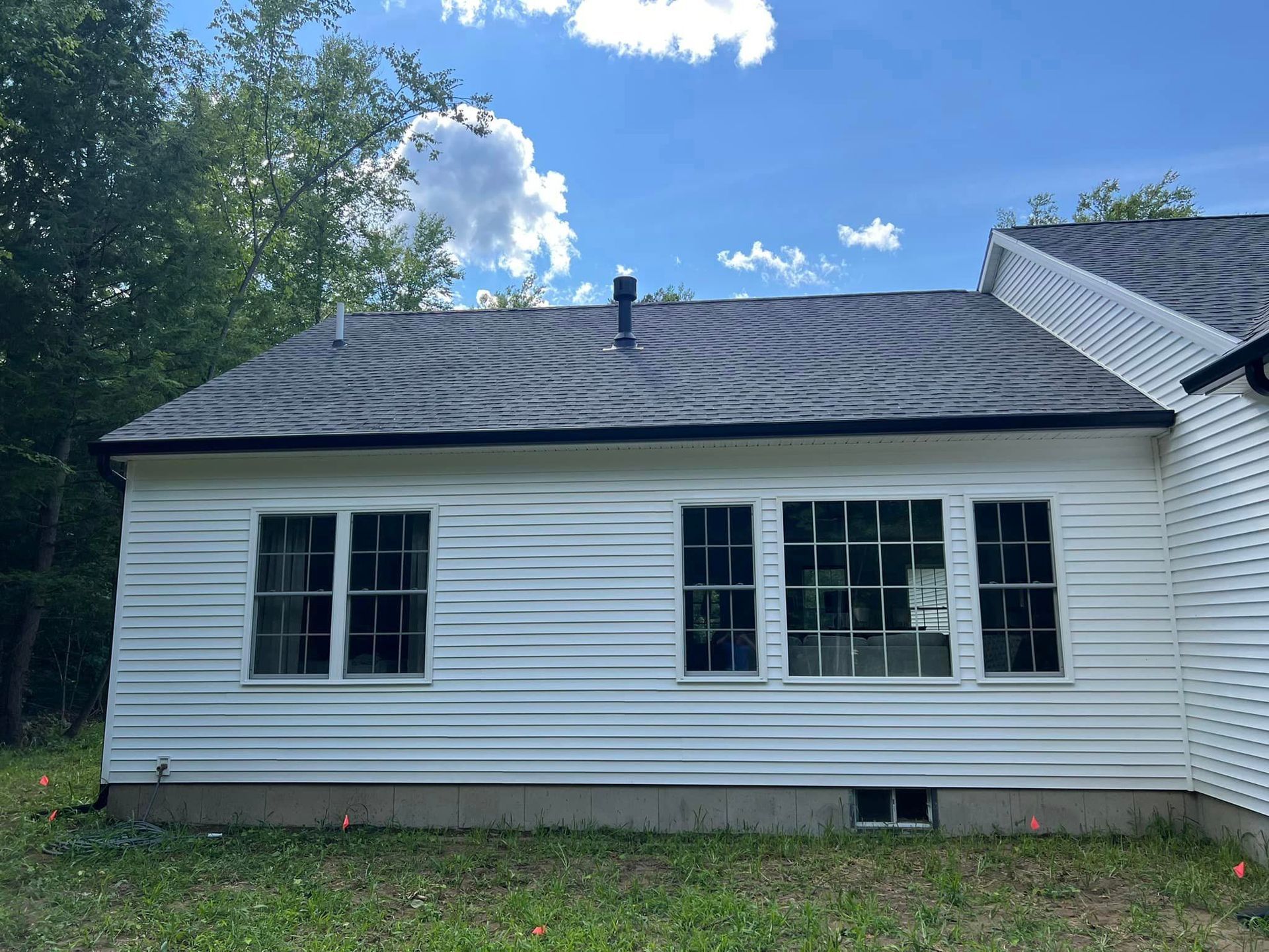The back of a white house with a black roof and a lot of windows