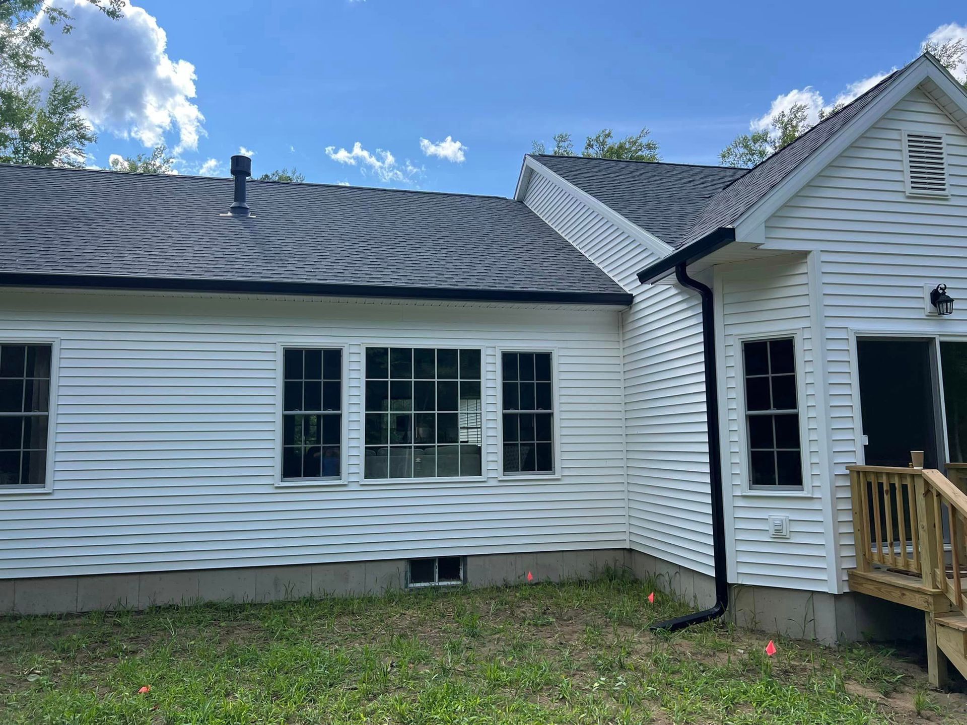 The back of a white house with a gray roof and a deck