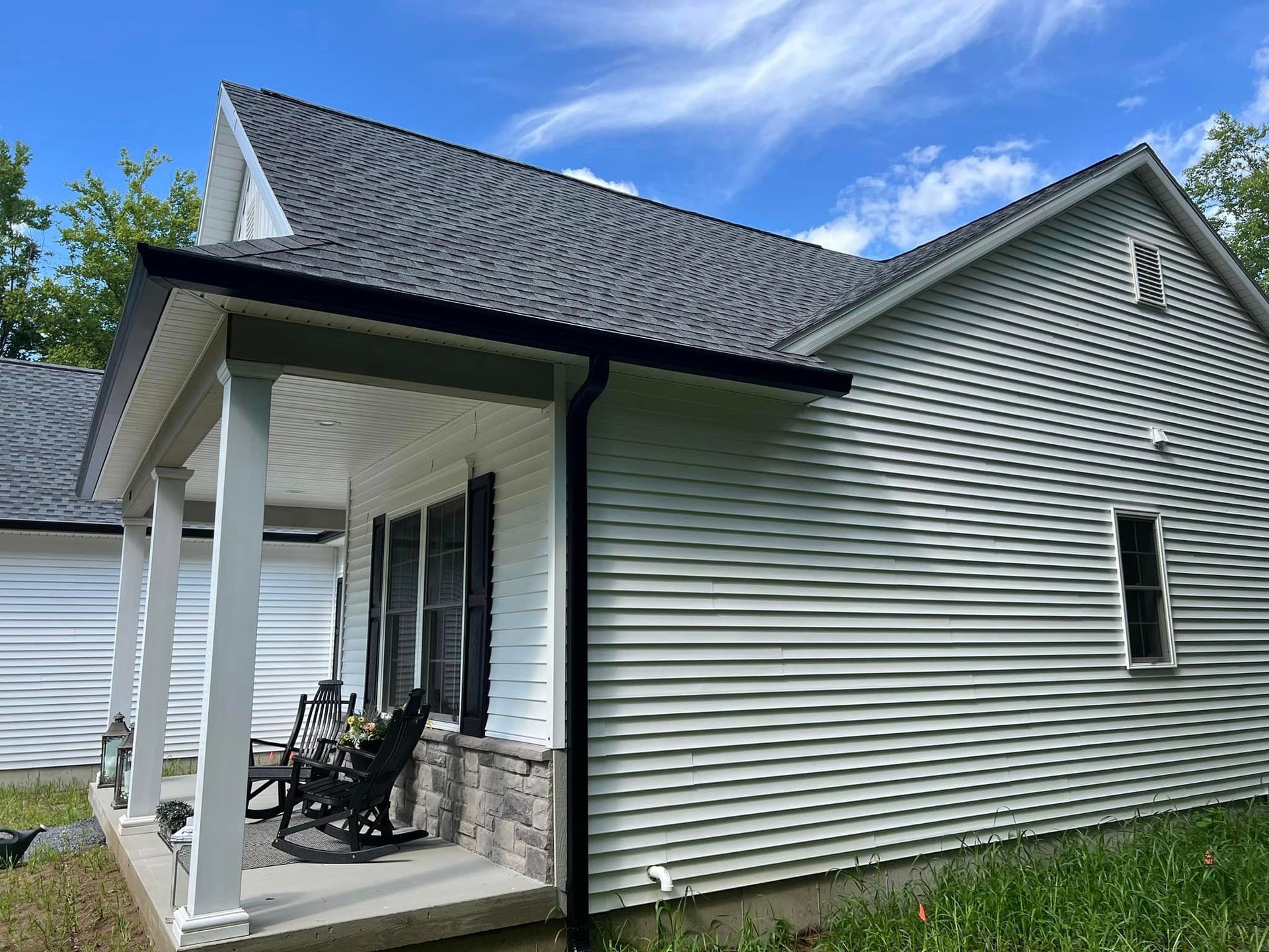 A white house with a porch and rocking chairs on it