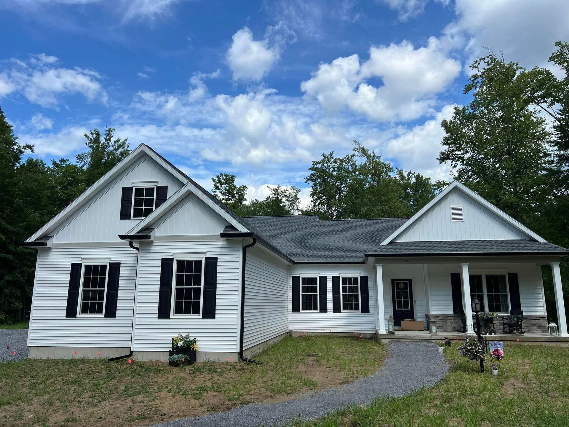 A white house with black shutters and a blue sky in the background