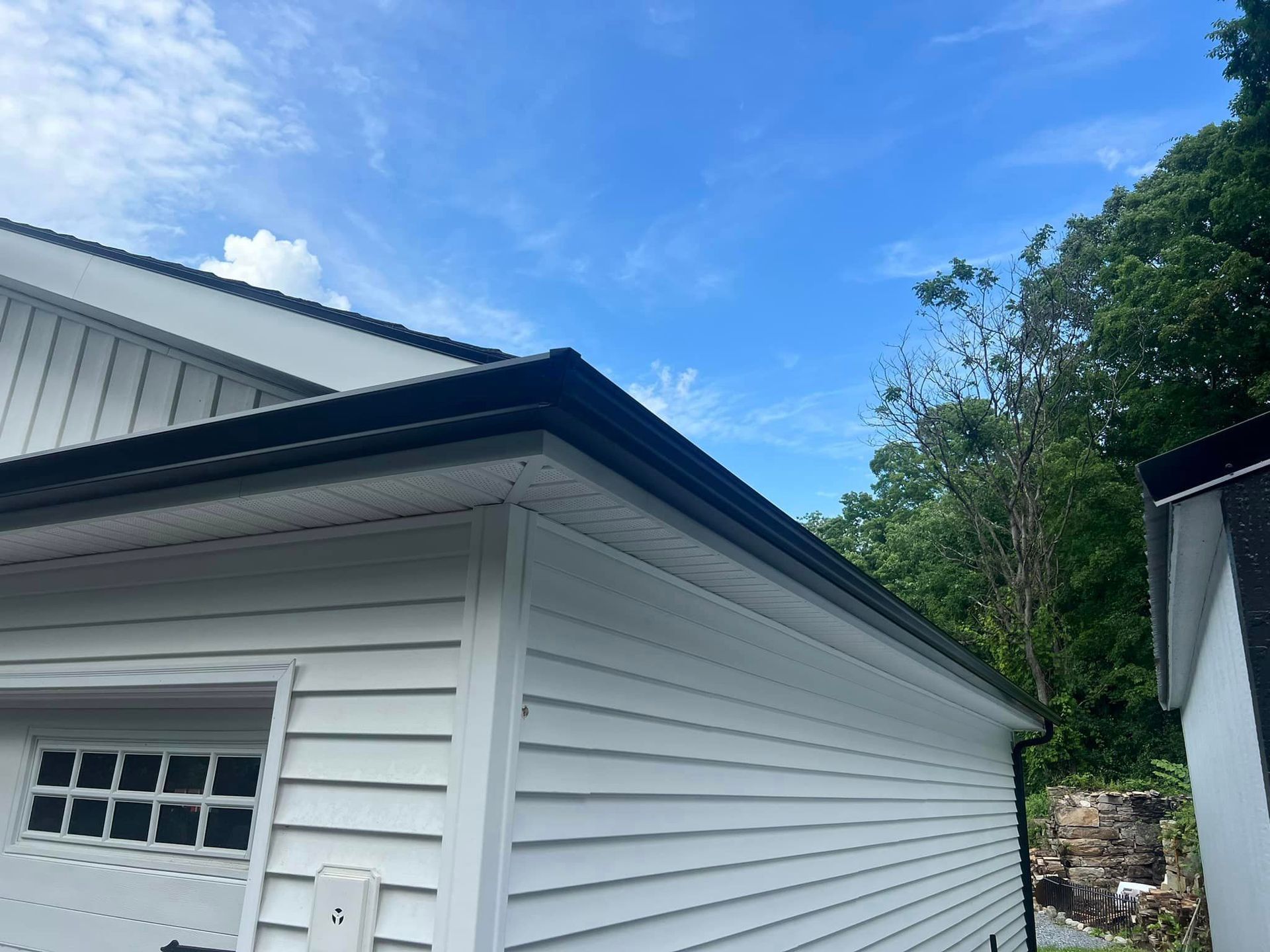 A white house with a black gutter on the side of it