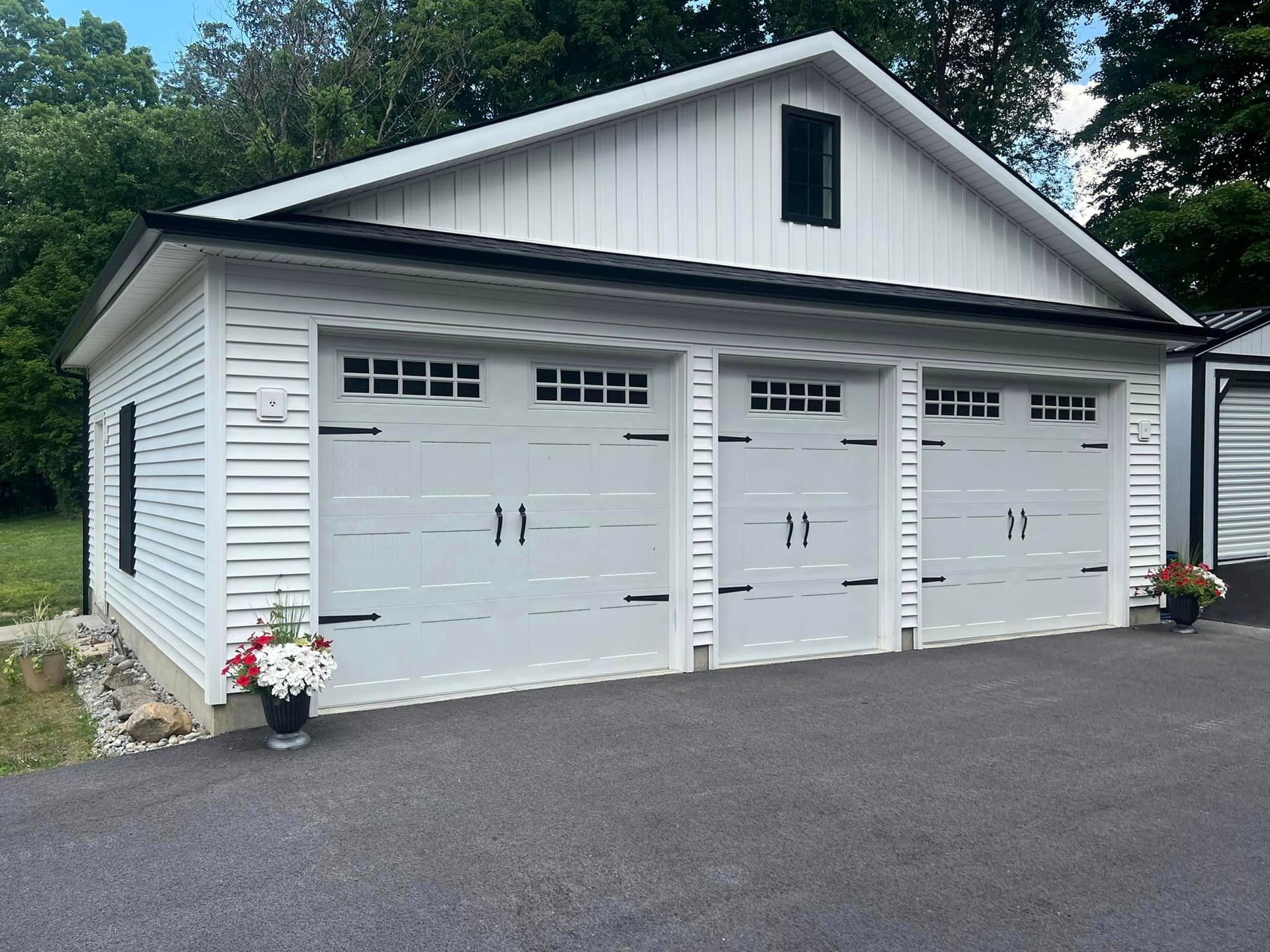 A white garage with three doors and a black roof