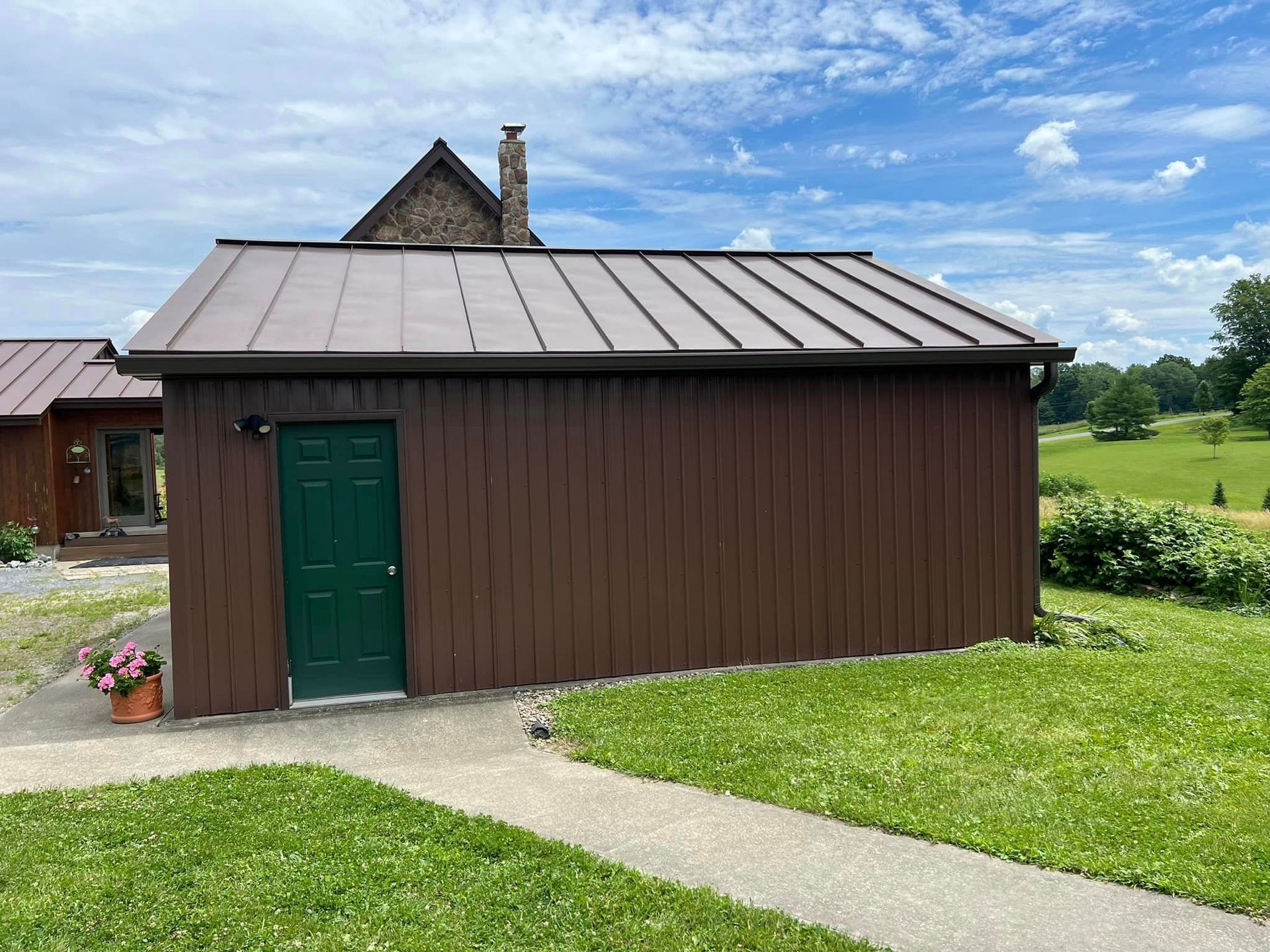 A small brown building with a green door and a metal roof