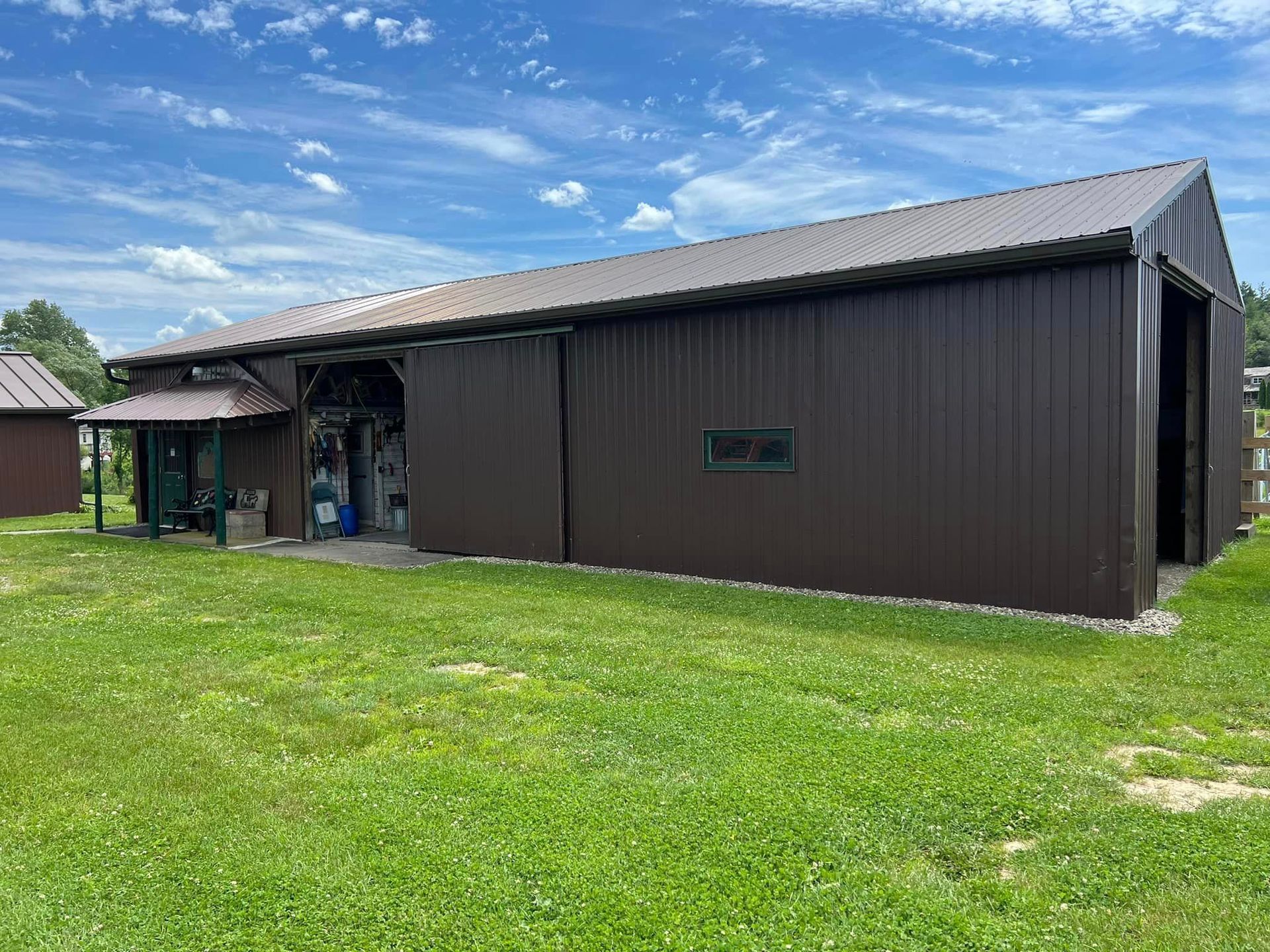 A large brown barn is sitting in the middle of a lush green field