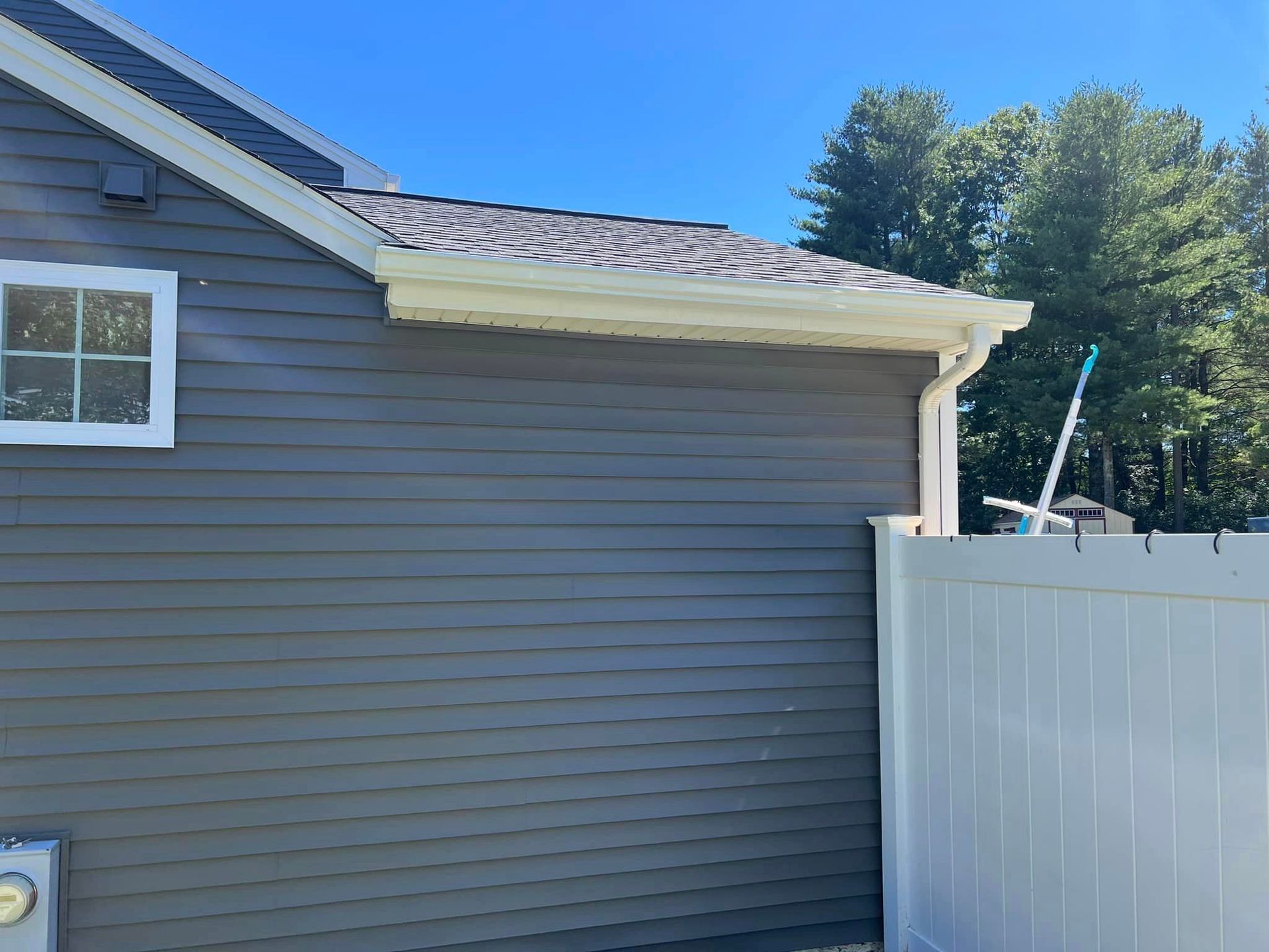 The side of a house with a white fence and a window