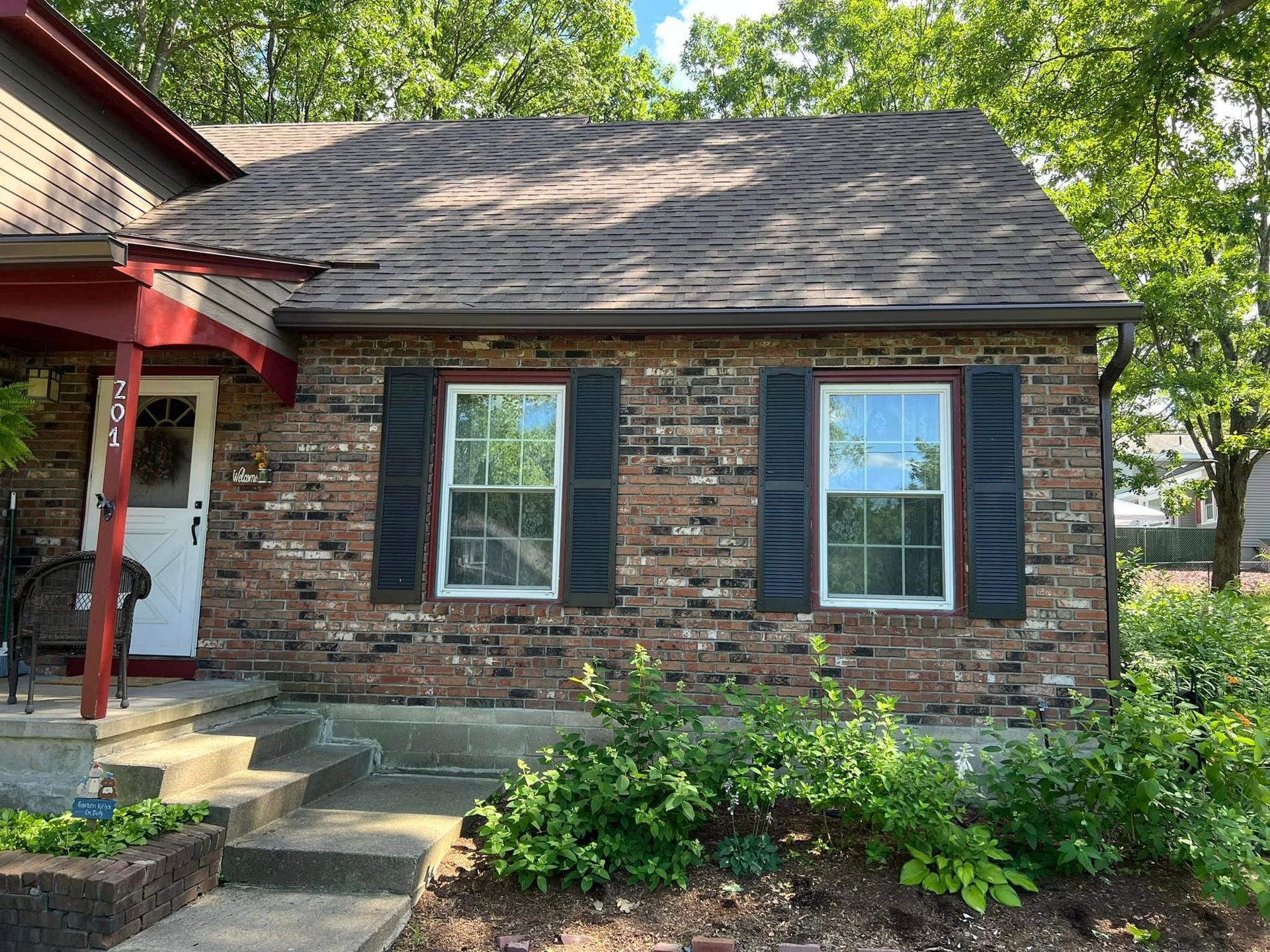A small brick house with black shutters on the windows