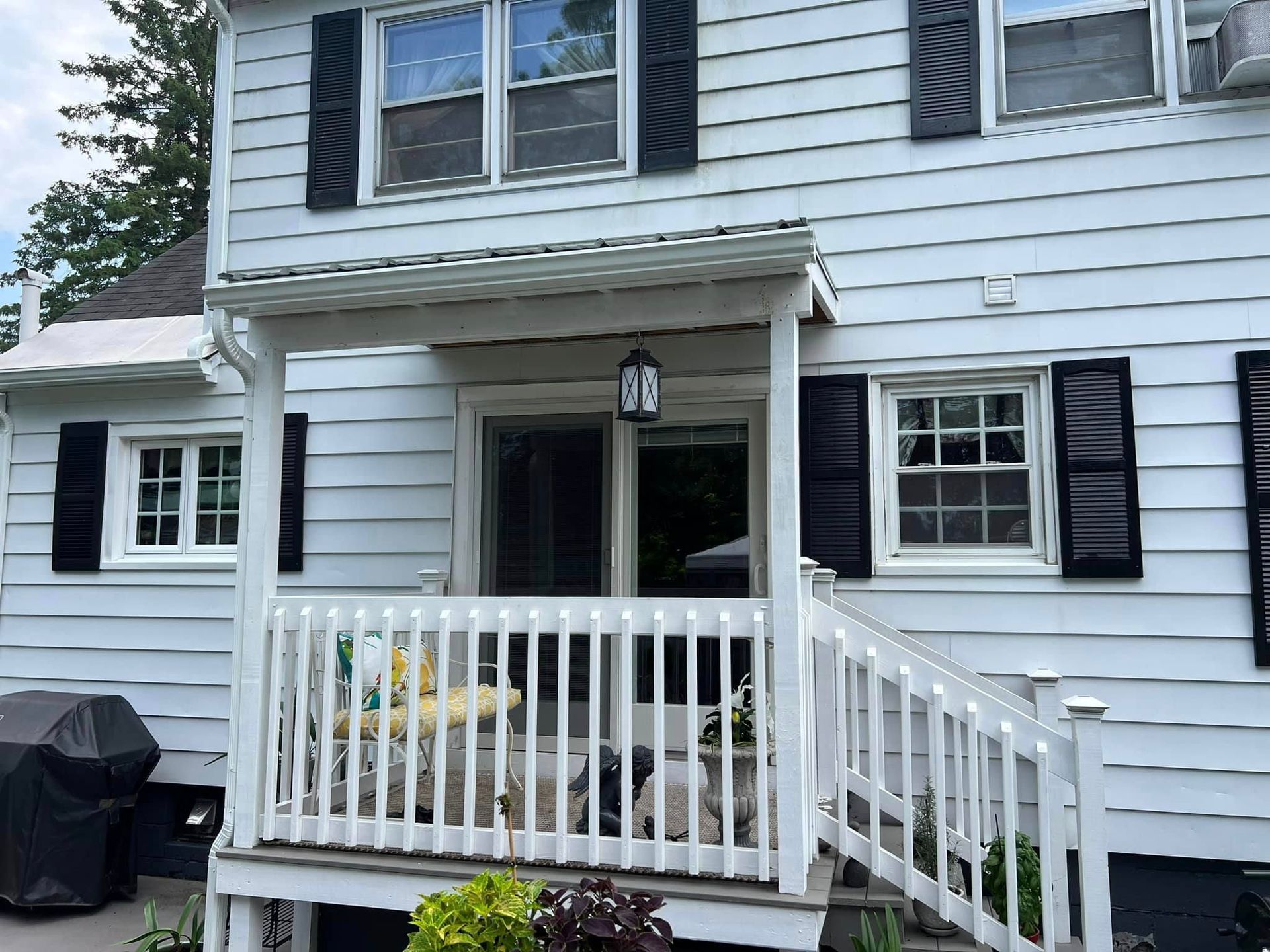 A white house with black shutters and a white porch