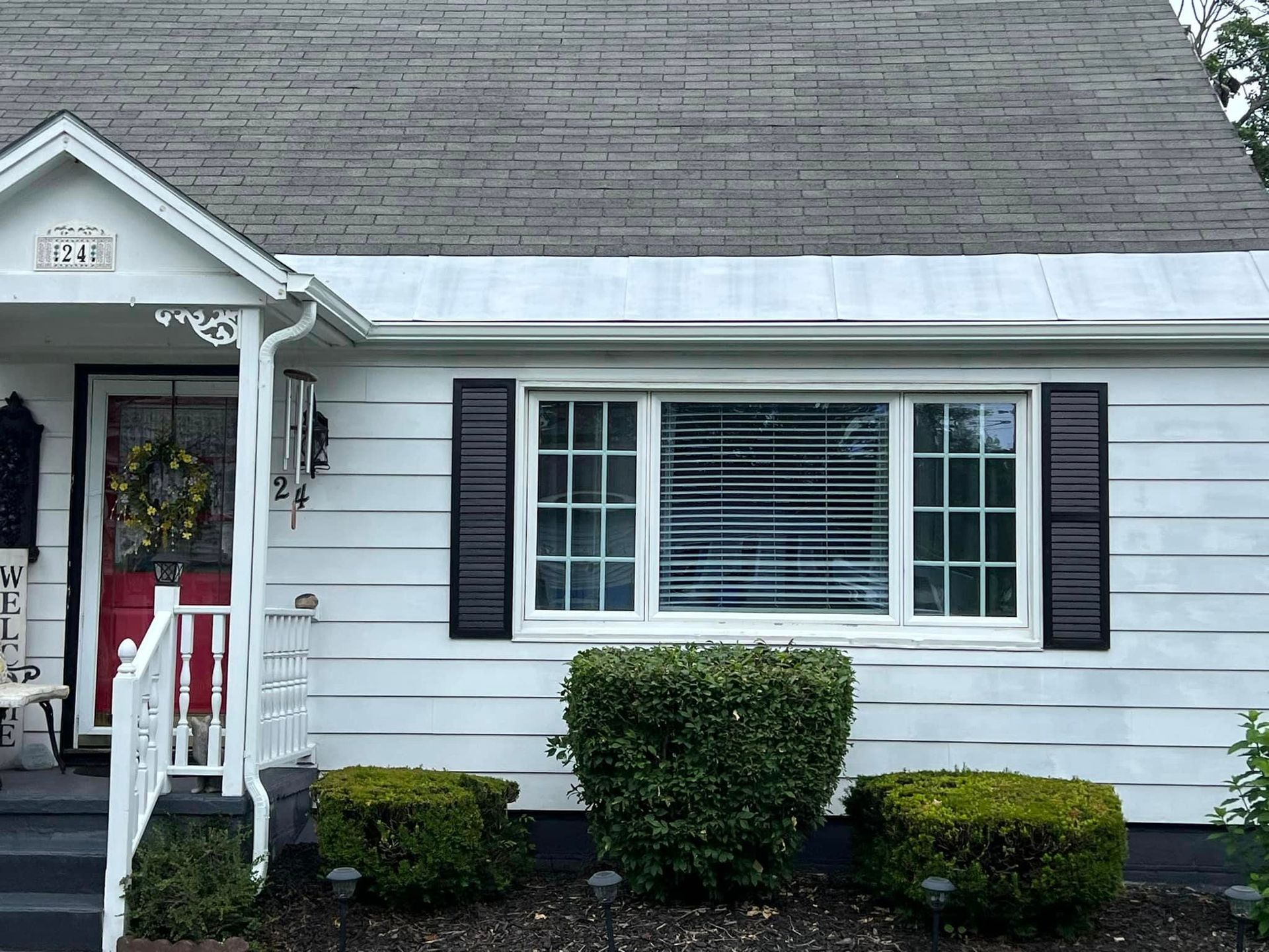 A white house with black shutters and a red door