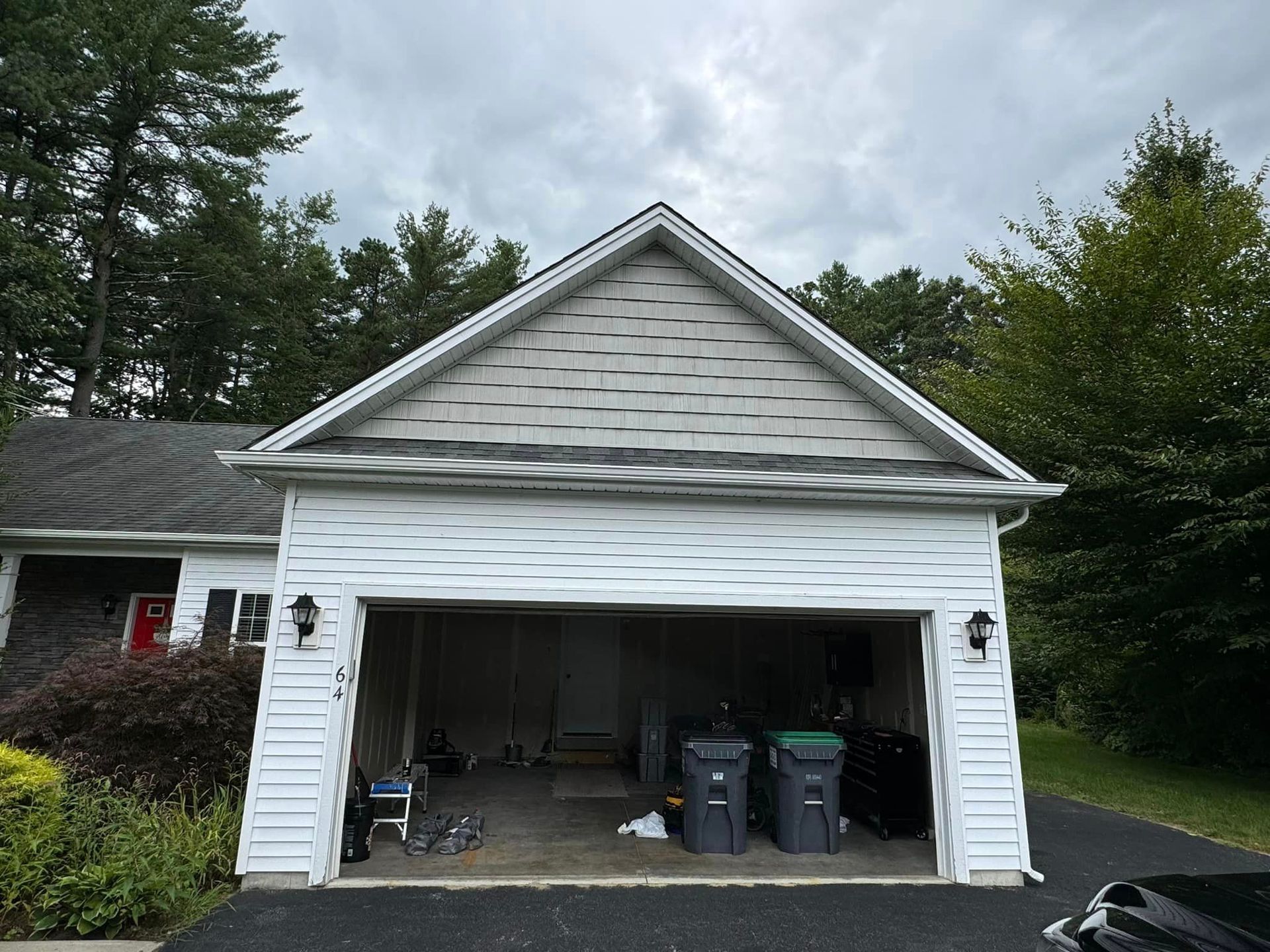 A white garage with a black car parked in front of it