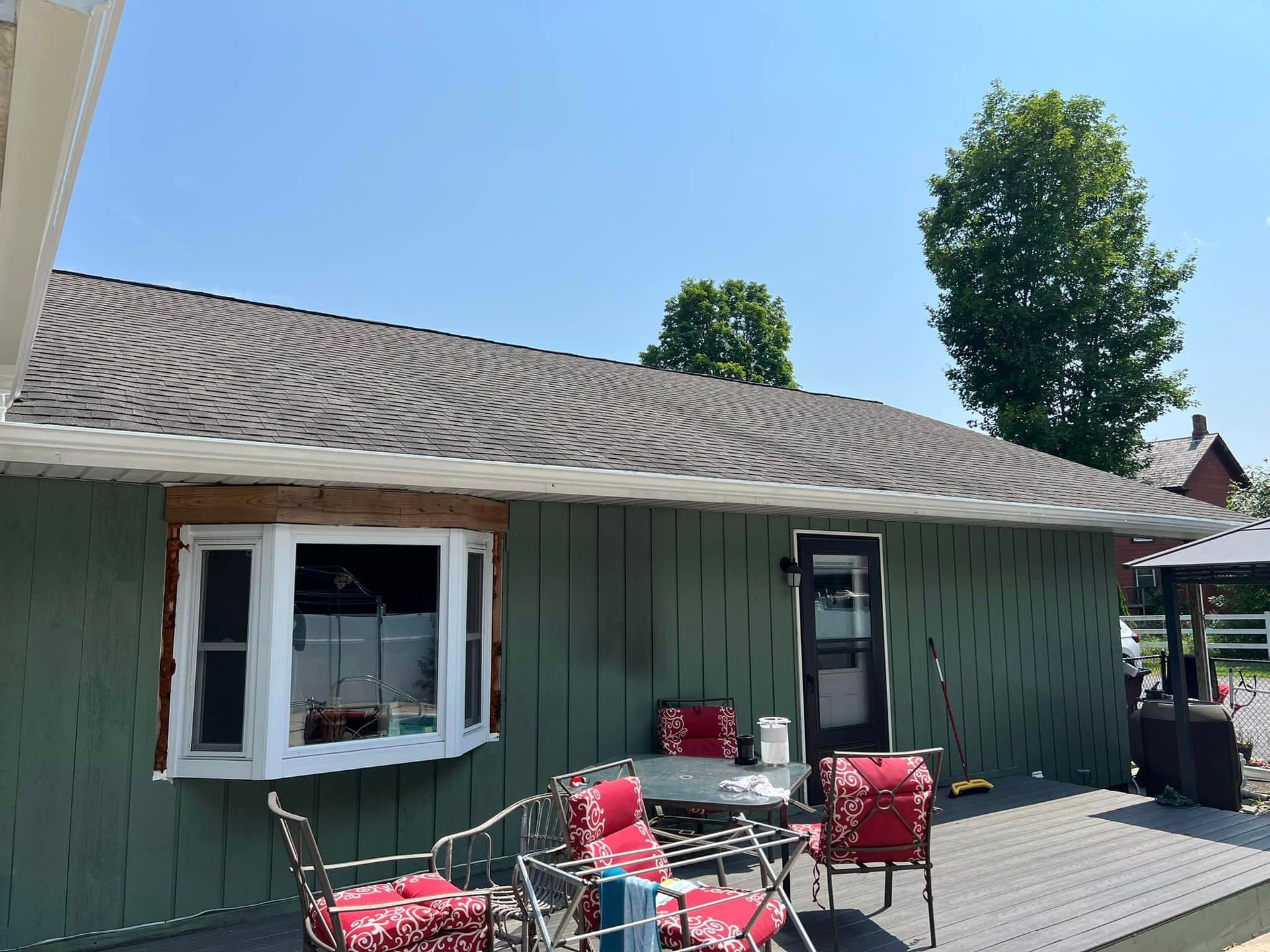 A green house with a deck and patio furniture in front of it